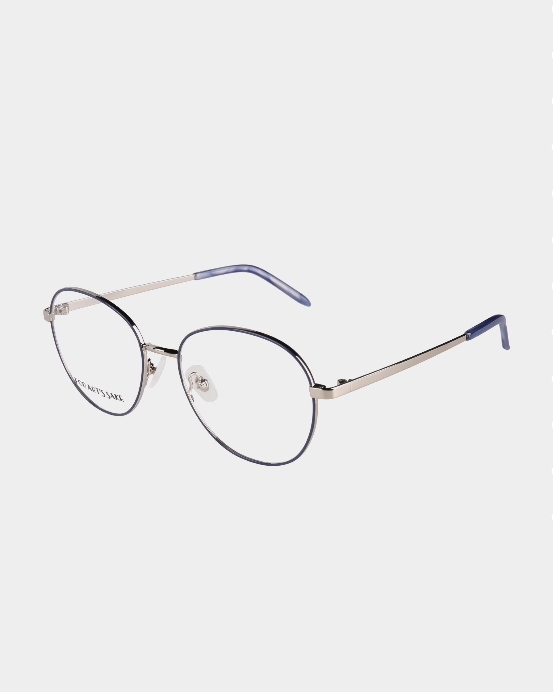A pair of sleek, round-framed Hailey eyeglasses by For Art&#39;s Sake® with a metallic silver bridge and temples. The temple tips are blue, and the frame has a subtle blue accent around the rims. Featuring adjustable nose pads for comfort, the clear lenses can include a Blue Light Filter for added eye protection.