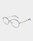 A pair of sleek, round-framed Hailey eyeglasses by For Art's Sake® with a metallic silver bridge and temples. The temple tips are blue, and the frame has a subtle blue accent around the rims. Featuring adjustable nose pads for comfort, the clear lenses can include a Blue Light Filter for added eye protection.