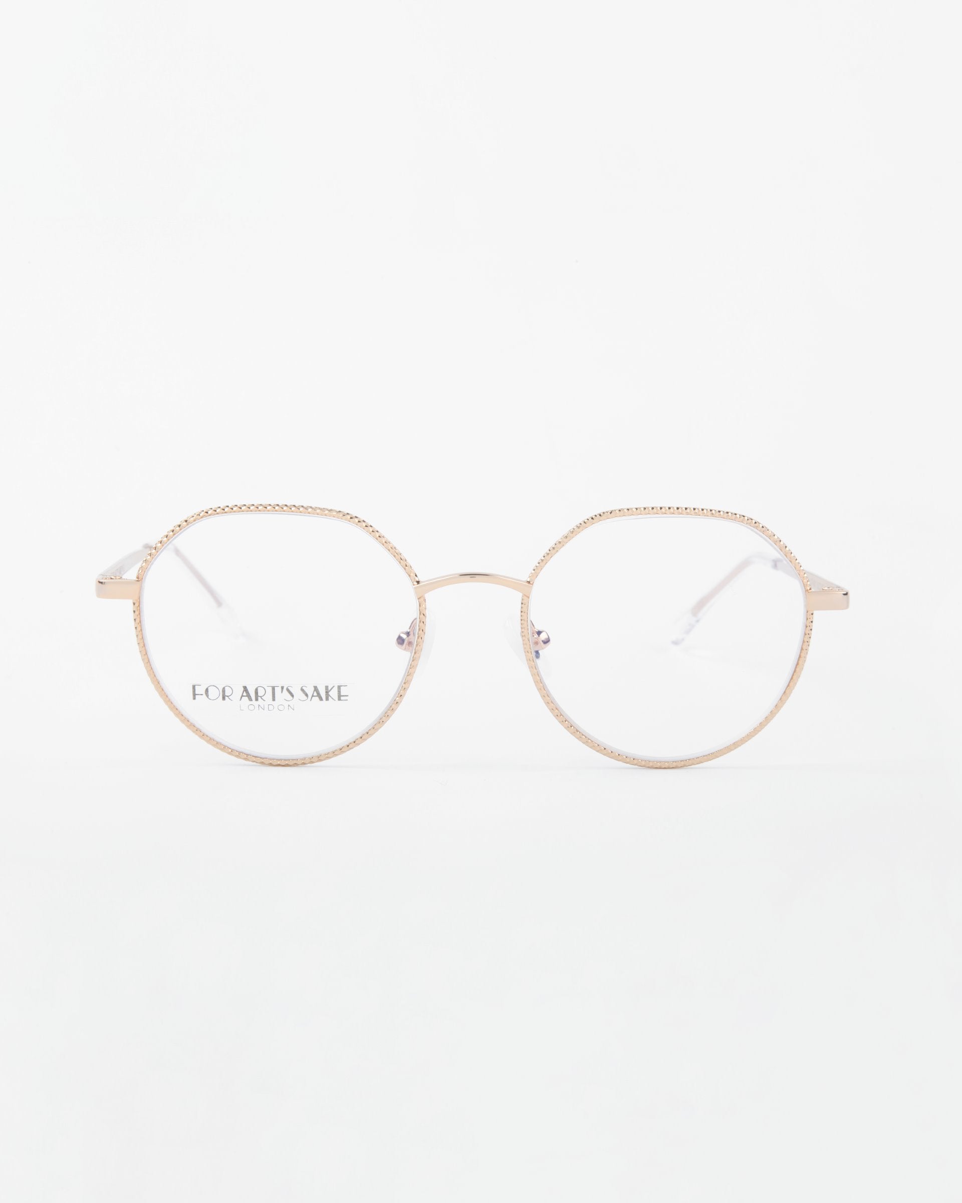 A pair of Hope eyeglasses by For Art&#39;s Sake® with thin, 18-karat gold-plated frames and clear lenses. The words &quot;For Art&#39;s Sake&quot; are visible on one of the lenses. The background is white, emphasizing the minimalist design of the glasses. These stylish frames can also come with a Blue Light Filter for added protection.