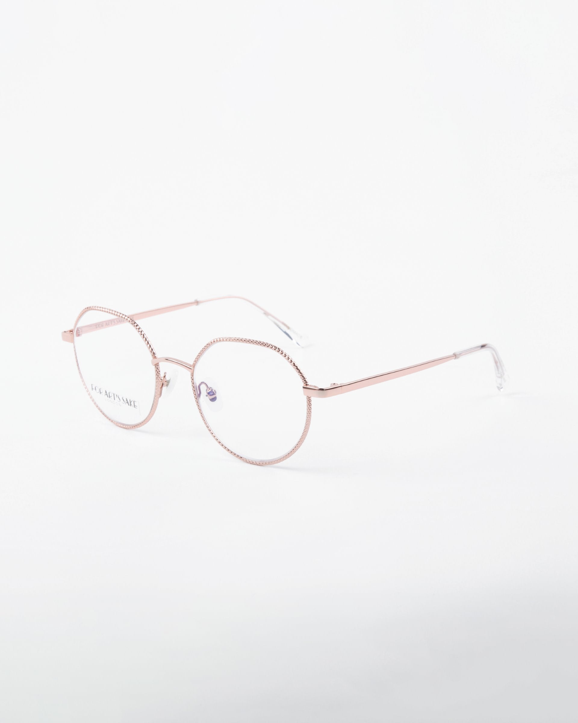 A pair of round, 18-karat gold-plated rose-gold eyeglasses with a thin metallic frame and transparent nose pads from For Art&#39;s Sake®, named Hope. The glasses are set against a white background, providing a clear view of the delicate design and subtle detailing on the frame.