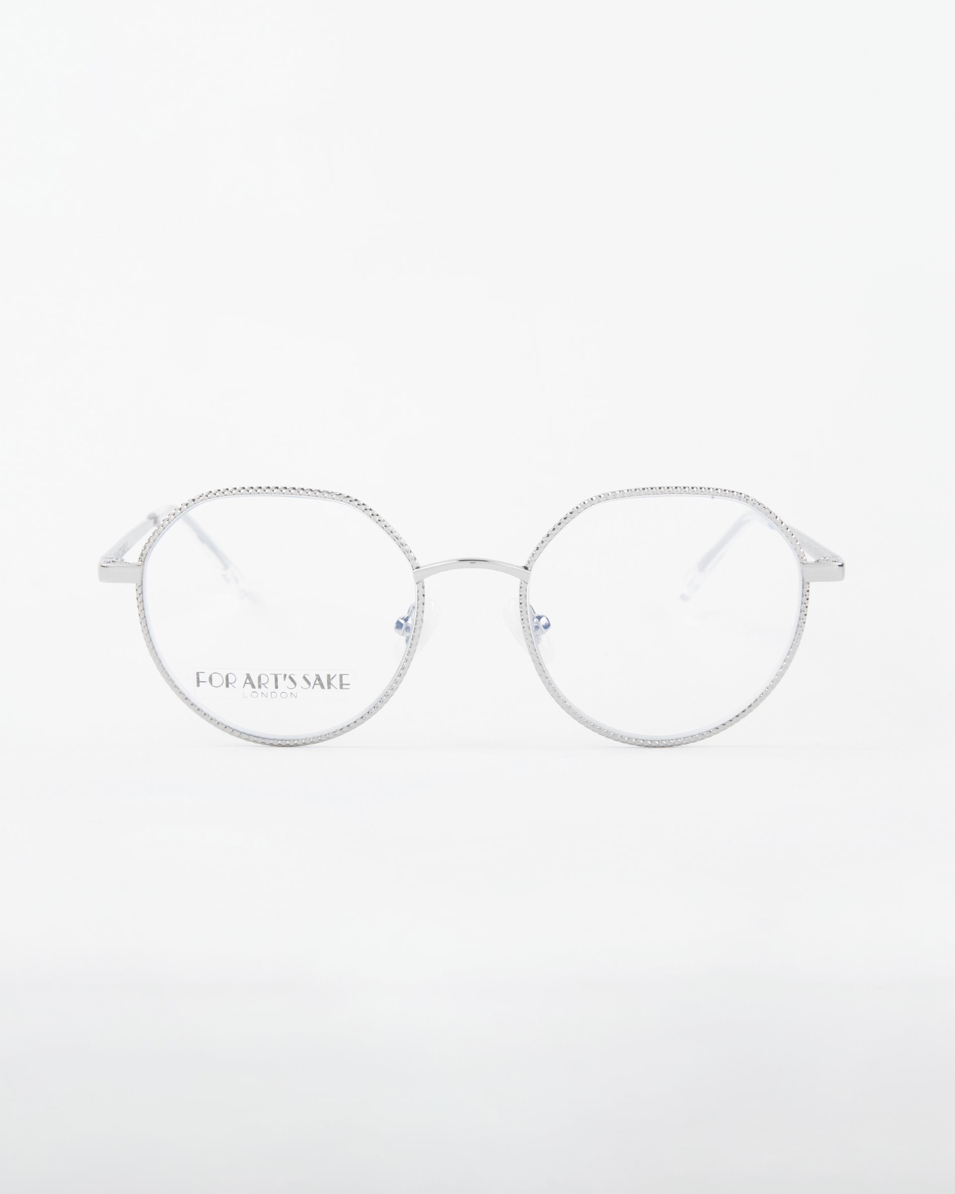 A pair of round, silver-framed eyeglasses with a delicate design, featuring an 18-karat gold-plated finish. The brand name For Art's Sake® is subtly inscribed on the left lens. The background is a clean, minimalistic white. This elegant piece is aptly named "Hope.