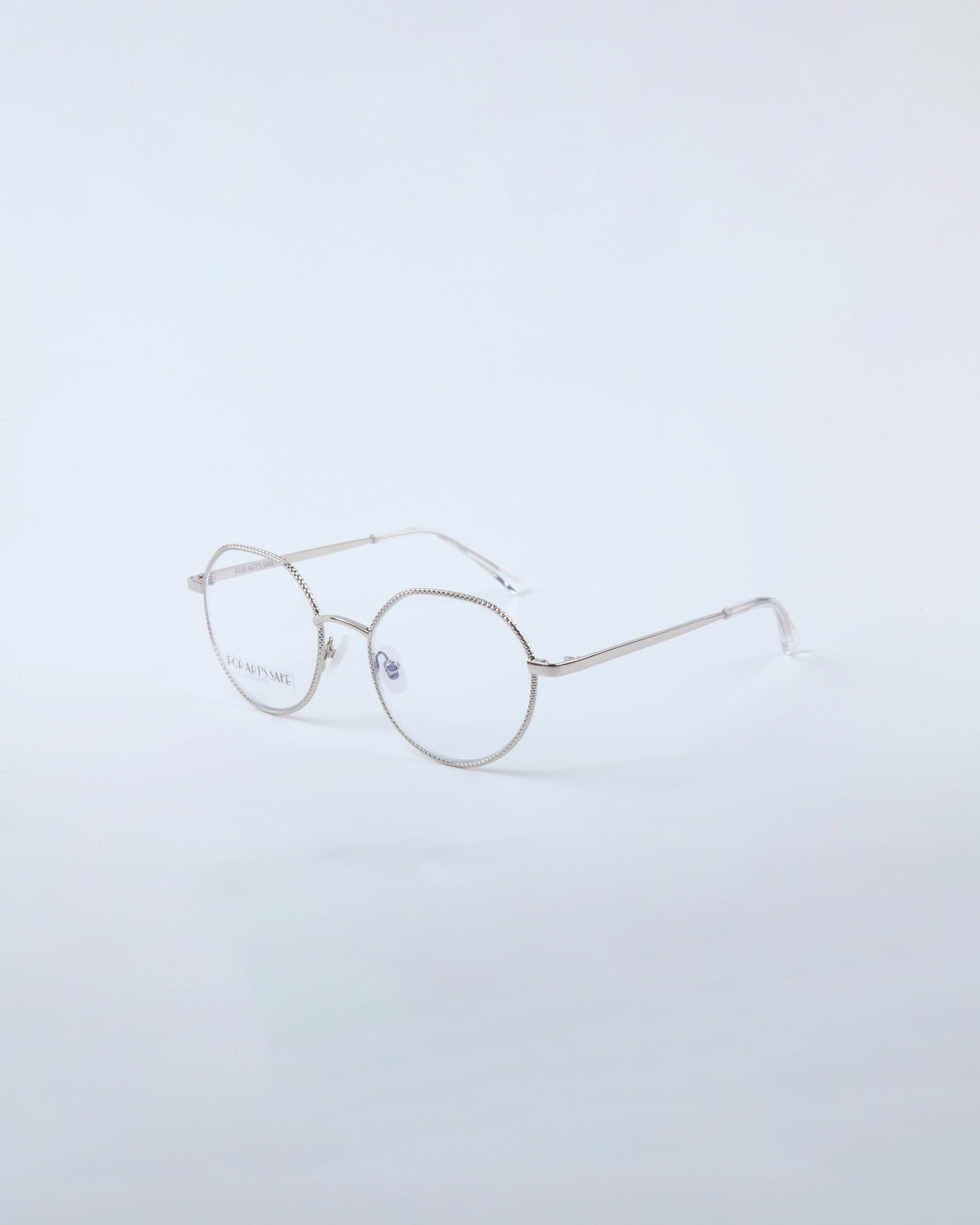 The Hope Silver eyeglasses by For Art's Sake® feature a unisex silhouette with round, thin frames and clear lenses against a plain, light background.