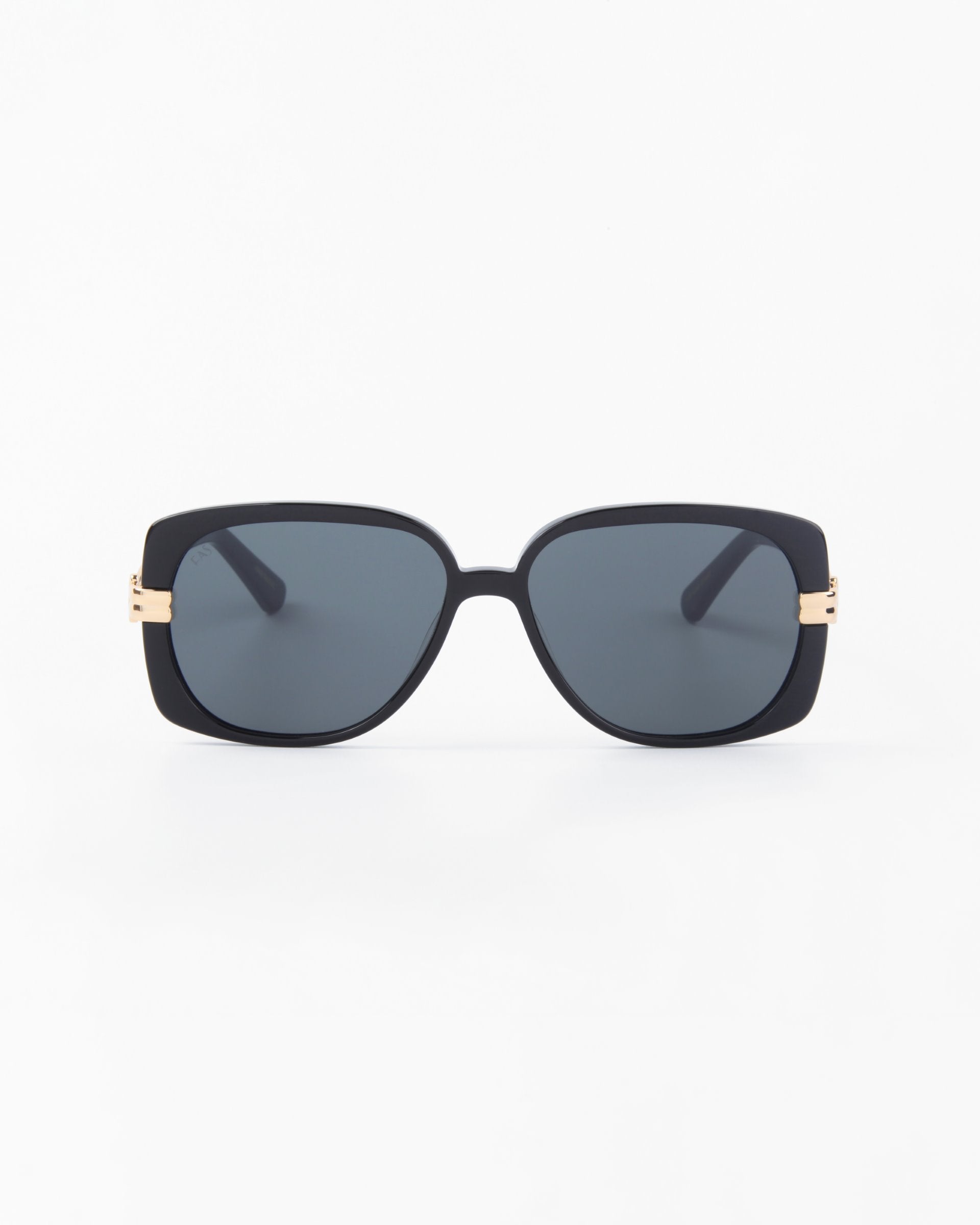 A pair of black rectangular For Art's Sake® Icon sunglasses with dark, shatter-resistant nylon lenses. The sunglasses have thin temples, small gold accents near the hinges, and offer full UVA & UVB protection. Handmade with precision, they are set against a plain white surface.