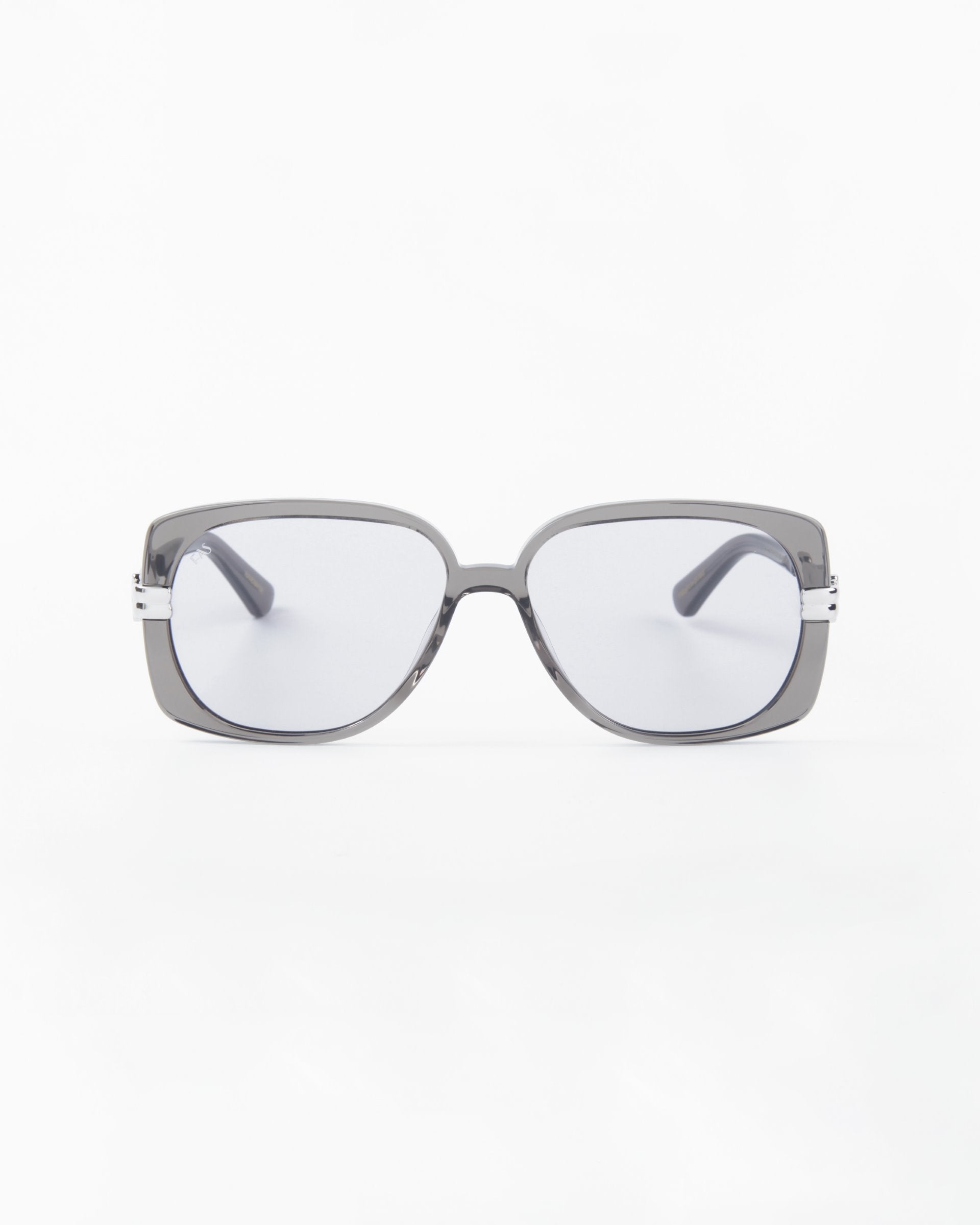 A pair of modern, gray-framed Icon sunglasses by For Art&#39;s Sake® with rectangular, shatter-resistant nylon lenses on a plain white background. The Icon sunglasses by For Art&#39;s Sake® are handmade, boasting a sleek and minimalist design with slightly curved arms and a polished finish.