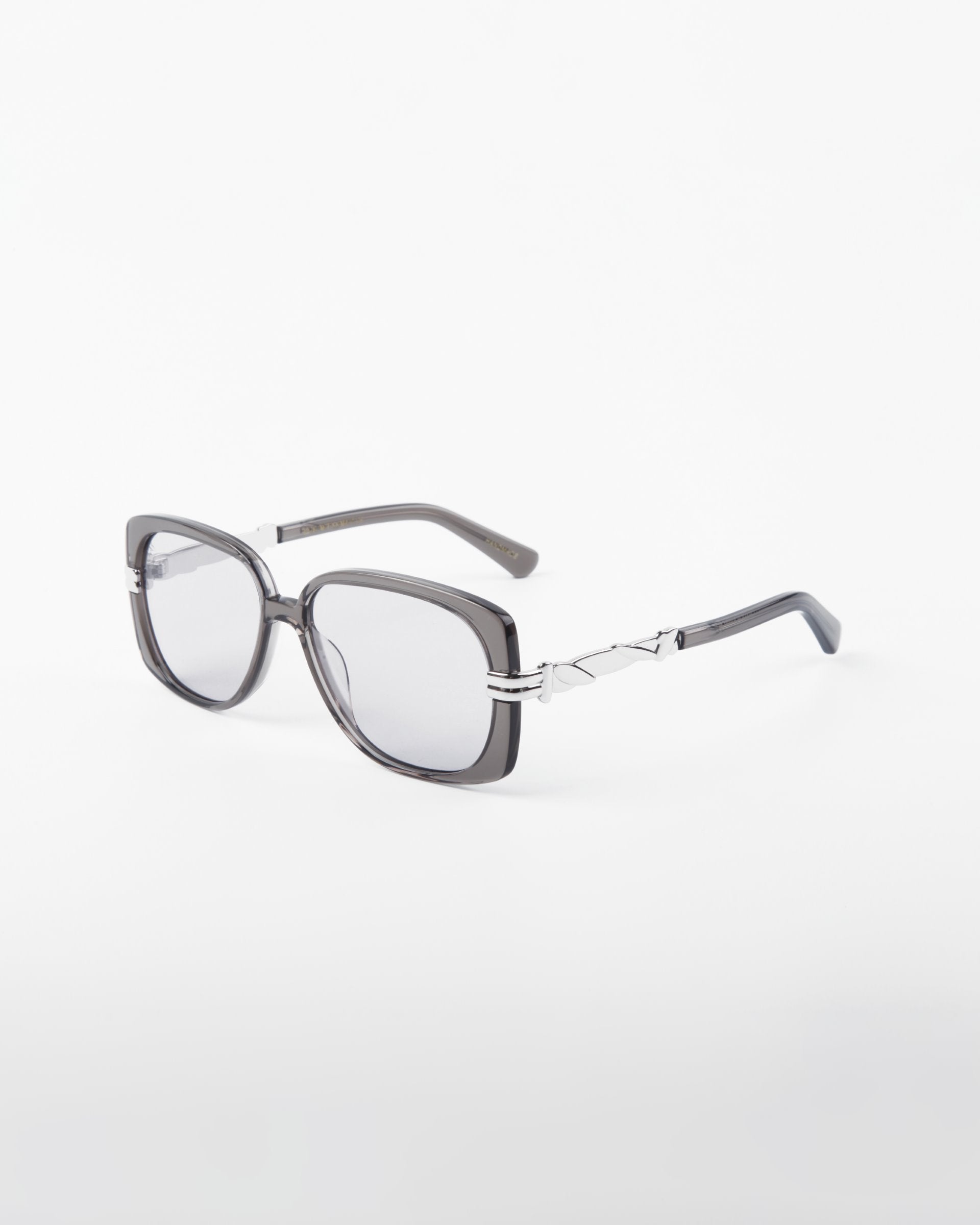 A pair of For Art's Sake® Icon rectangular sunglasses with silver metal frames and dark grey shatter-resistant nylon lenses lies on a white background. The UVA & UVB-protected temples are adorned with geometric cut-out designs, adding a modern touch to the glasses.