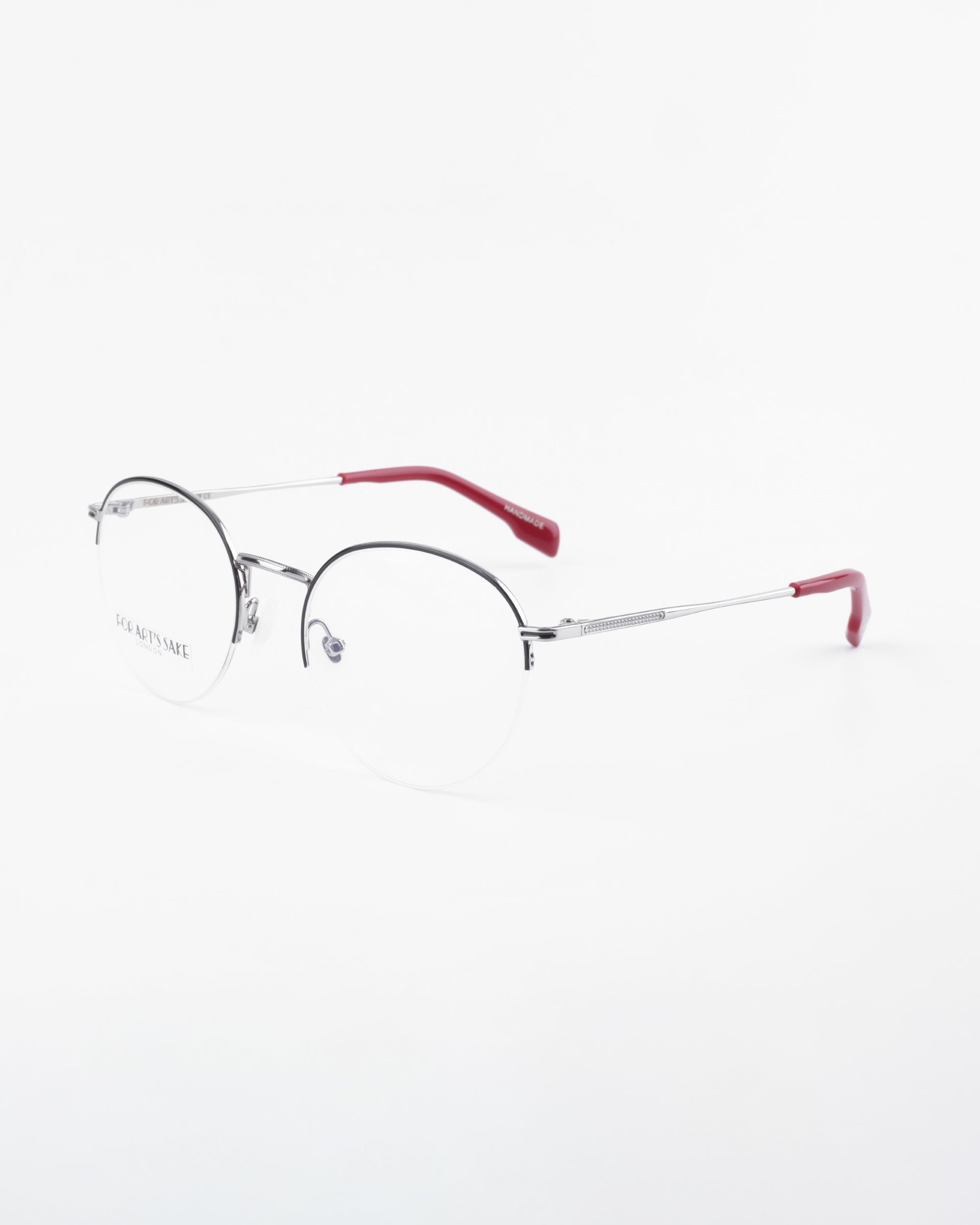 A pair of Ivy by For Art&#39;s Sake® with thin, silver metal frames and red earpieces. The design is minimalistic and modern, featuring adjustable nose pads for comfort and prescription lenses with a blue light filter. The brand&#39;s name is subtly visible on one side of the frame, set against a white background.