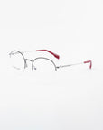 A pair of Ivy by For Art's Sake® with thin, silver metal frames and red earpieces. The design is minimalistic and modern, featuring adjustable nose pads for comfort and prescription lenses with a blue light filter. The brand's name is subtly visible on one side of the frame, set against a white background.