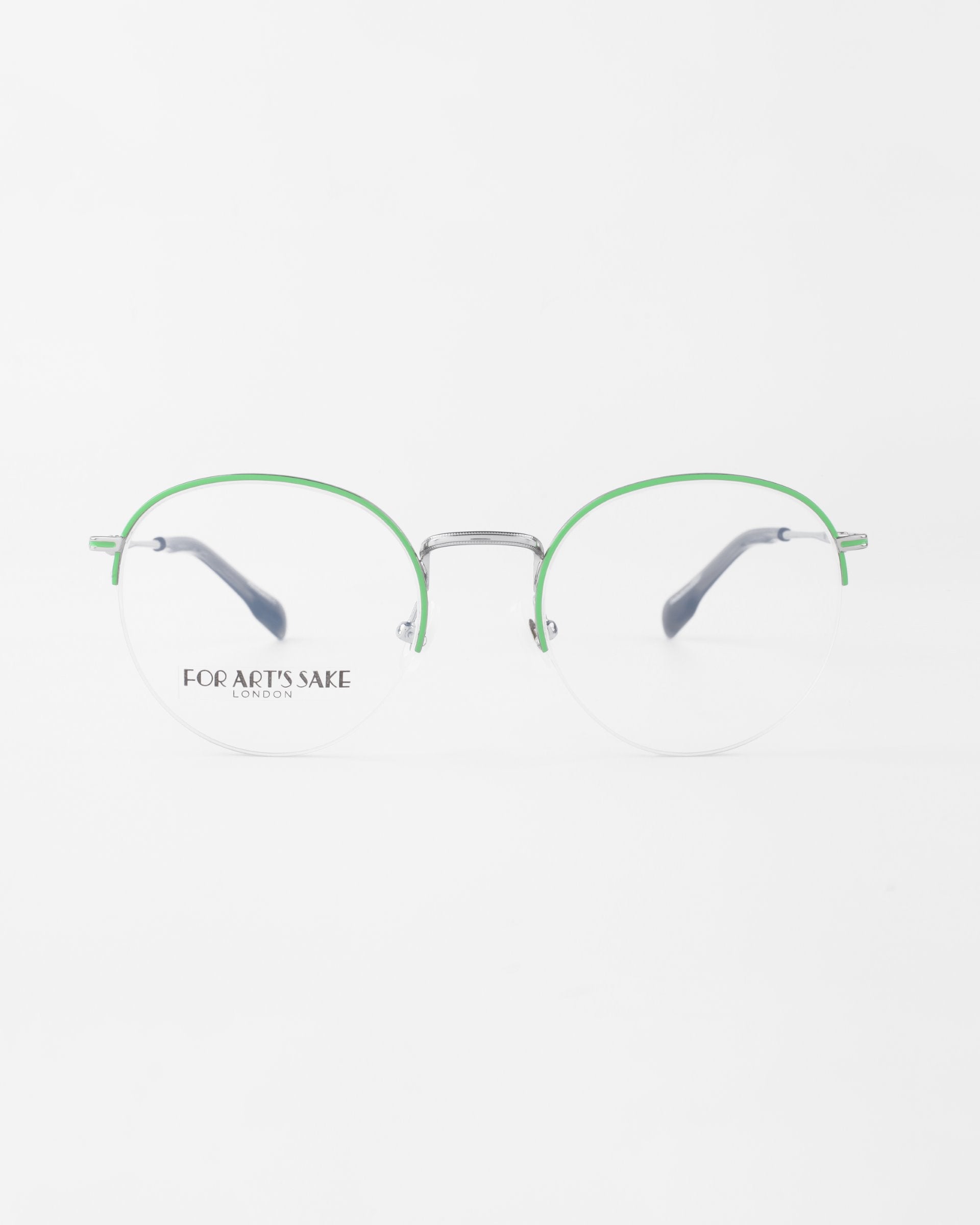 A pair of Ivy eyeglasses with thin, green metal frames and clear lenses featuring a blue light filter. The temples are silver and tipped in black. The brand name &quot;For Art&#39;s Sake®&quot; is visible on the left lens. The eyeglasses are set against a plain white background.