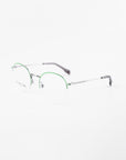 A pair of For Art's Sake® Ivy eyeglasses with thin silver metal frames and green accents on the upper rims. The glasses, featuring clear round prescription lenses with a blue light filter, and dark-colored temple tips, are placed on a white background.