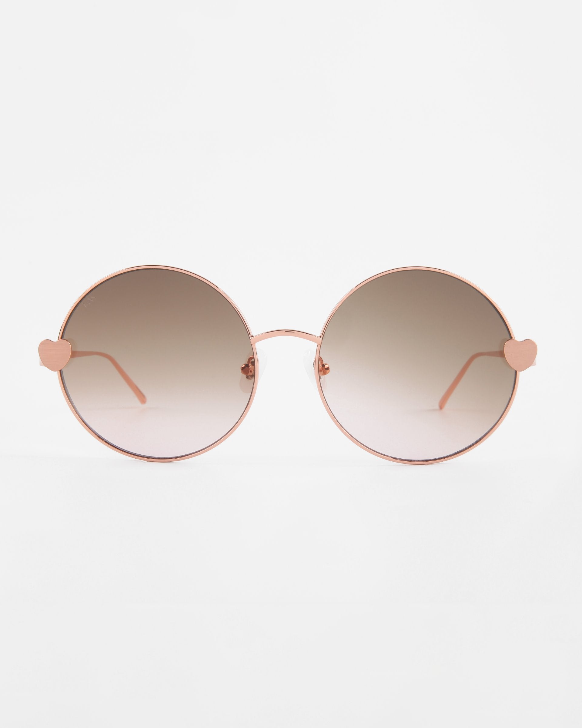 A pair of round, gradient-tinted **Love Story** shades from **For Art's Sake®** with thin, rose-gold frames. The temples feature small, heart-shaped decorations near the lenses and jadestone nose pads. The background is plain white, ensuring they stand out while offering 100% UV protection.