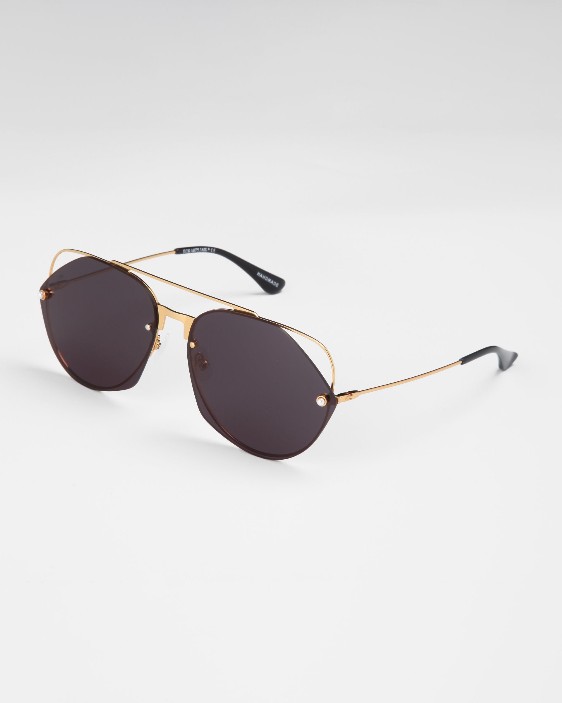 A pair of stylish aviator sunglasses with gold metal frames and dark tinted nylon lenses offering UV protection. The glasses have a sleek design with thin arms ending in black earpieces. The background is plain and white, reminiscent of the glamour found in Casino by For Art&#39;s Sake®.