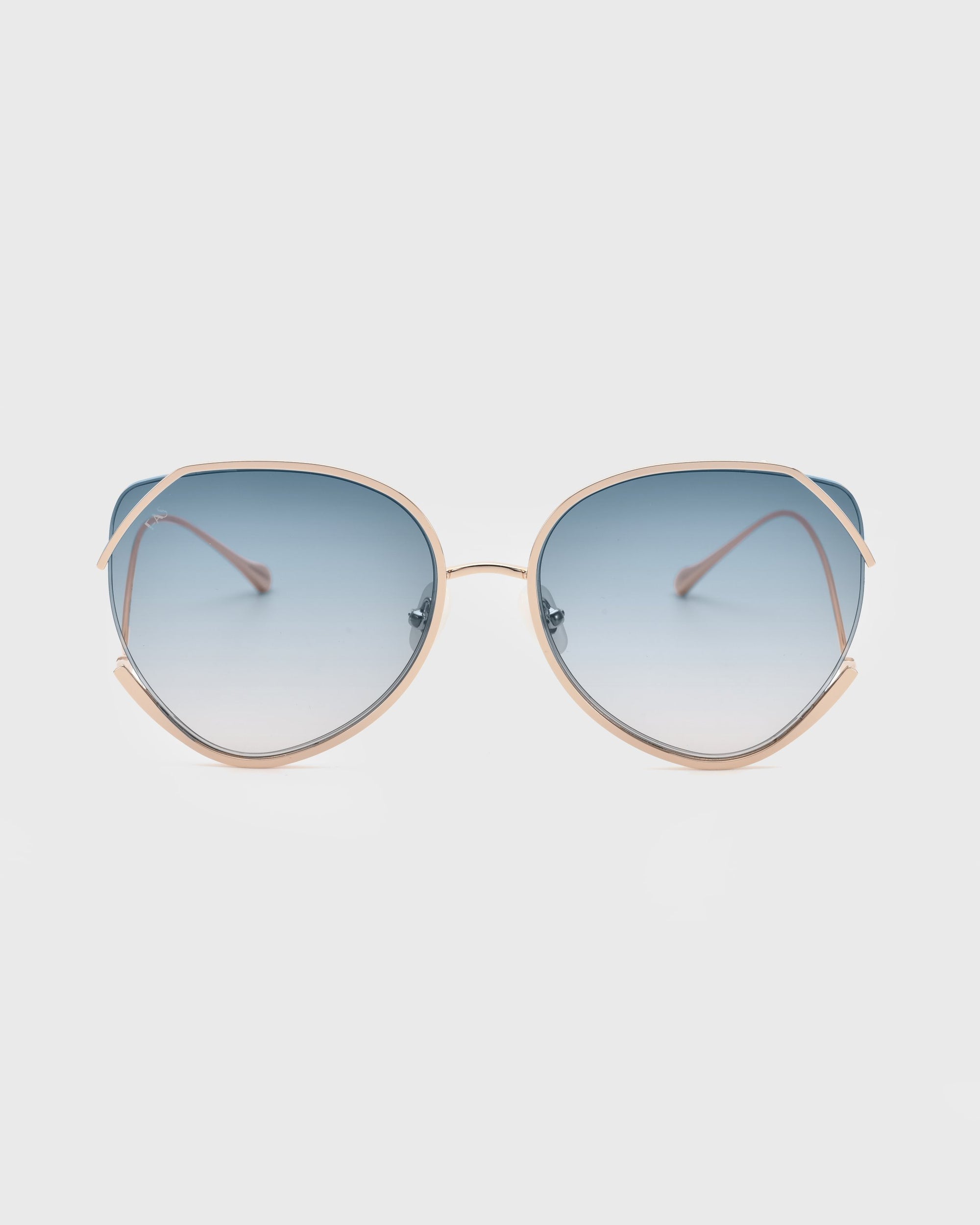 A pair of Wonderland sunglasses by For Art&#39;s Sake® with a thin, light-colored metal frame and large, teardrop-shaped blue gradient lenses. Equipped with jadestone nose pads for added comfort and UV protection, the arms of the glasses are also light-colored and slightly curved. The background is plain and white.
