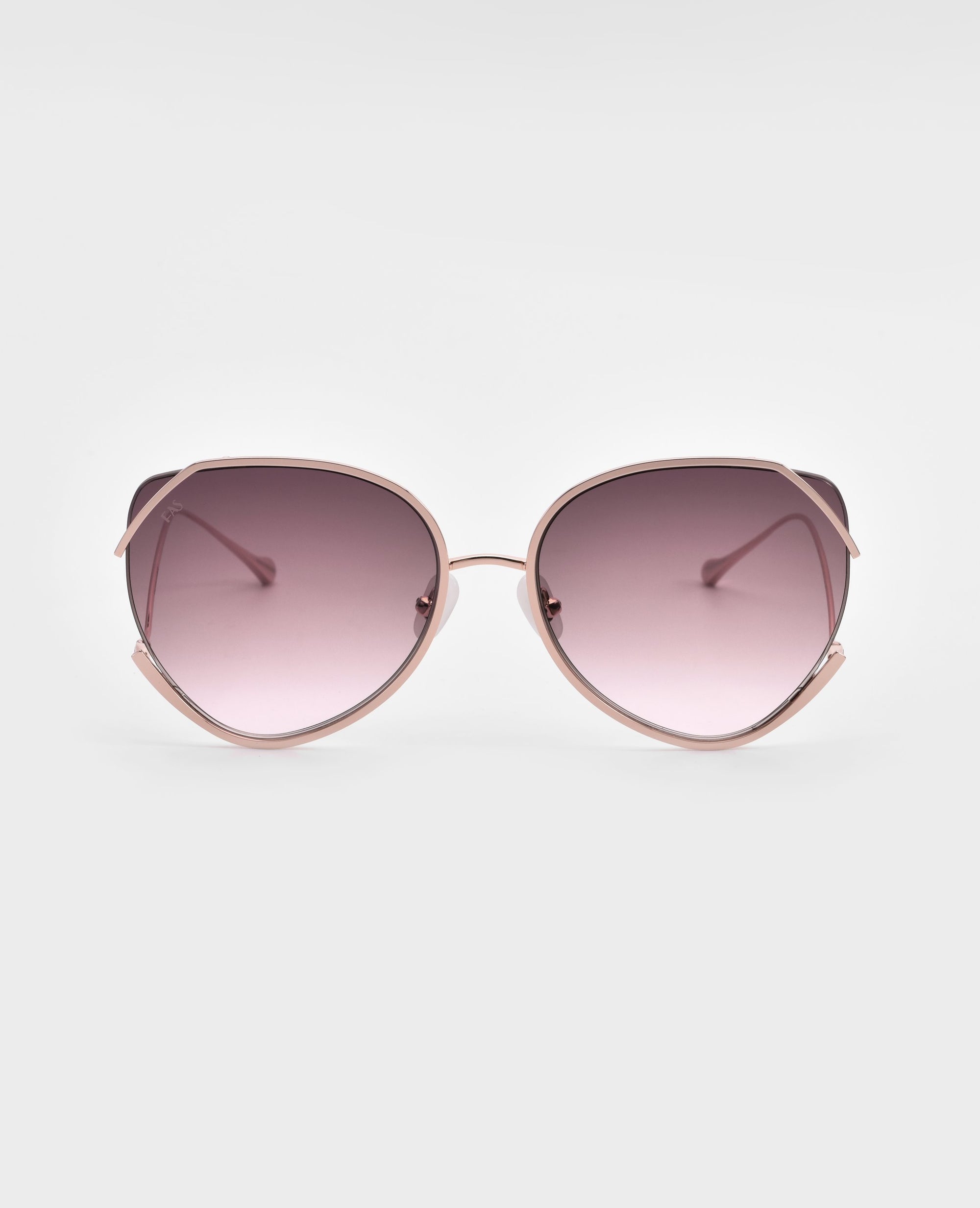 A pair of stylish Wonderland sunglasses by For Art's Sake® featuring large, round lenses with a gradient pink tint. The frame is gold-plated stainless steel with a light pink color, and the design includes emphasized curves on the edges of the lenses. Jadestone nosepads add comfort, while UVA & UVB protection ensures your eyes stay safe.