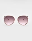 A pair of stylish Wonderland sunglasses by For Art's Sake® featuring large, round lenses with a gradient pink tint. The frame is gold-plated stainless steel with a light pink color, and the design includes emphasized curves on the edges of the lenses. Jadestone nosepads add comfort, while UVA & UVB protection ensures your eyes stay safe.