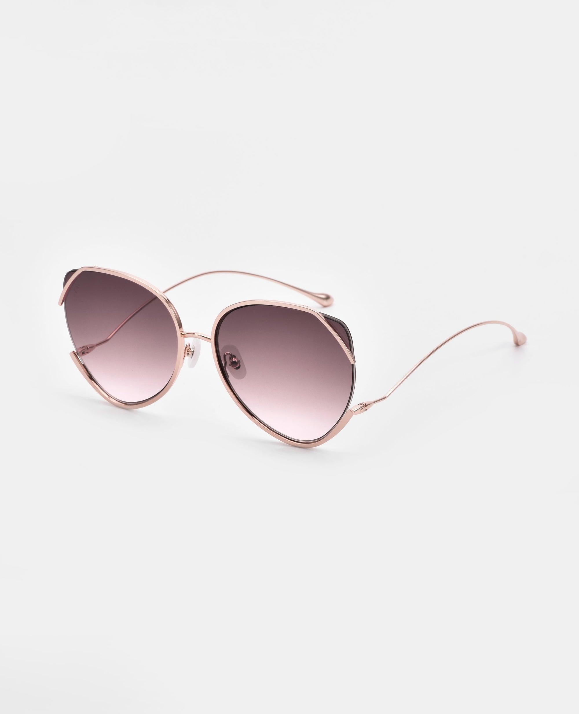 A pair of Wonderland cat-eye sunglasses by For Art&#39;s Sake® with gold-plated stainless steel frames and gradient pink lenses is displayed on a white background. The thin metal arms are slightly curved, adding a stylish detail to the chic design, while providing complete UVA &amp; UVB protection.