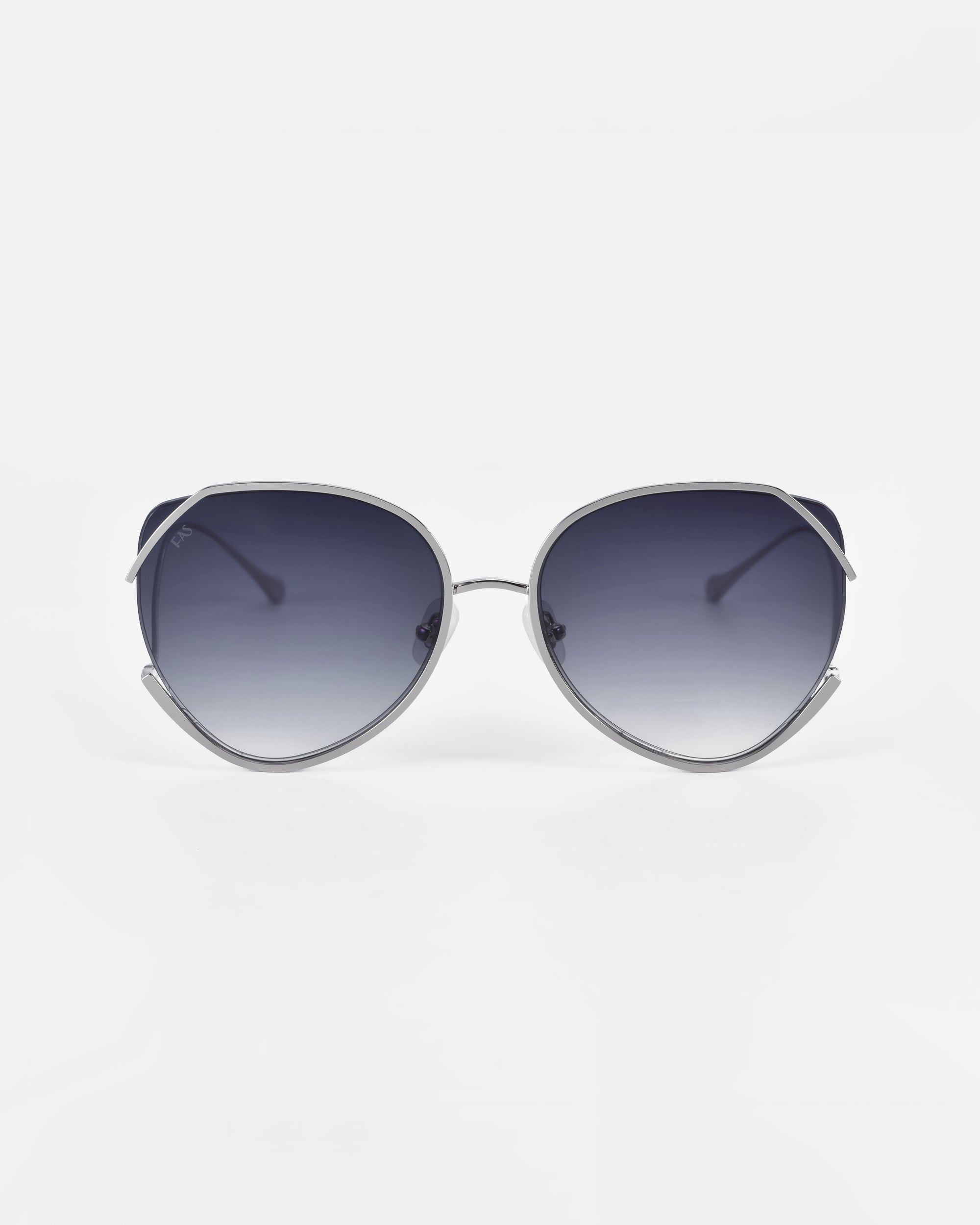 A pair of oversized, cat-eye sunglasses with thin metal frames and ultralightweight gradient lenses that provide 100% UV protection. The frames are sleek and metallic, complemented by jadestone nose pads for added comfort. The overall aesthetic is modern and chic. Introducing Wonderland by For Art's Sake®.