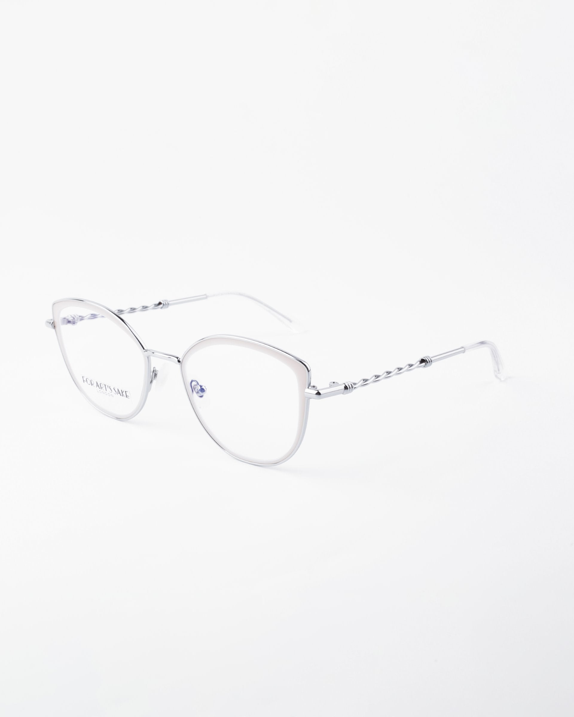 Clear, rectangular eyeglasses with metallic, thin, twisted arms. The lenses have a subtle tint and include a Blue Light Filter. The frame is adorned with small detailing near the hinges and 18-karat gold-plated accents. The temple tips are smooth and straight, set against a plain white background. These are the Julie by For Art&#39;s Sake®.