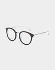 The Jackie eyeglasses by For Art's Sake® feature a pair of round frames crafted from plant-based acetate, showcasing black frames and thin metal temples. With clear lenses and a simple, minimalist design, these glasses stand out against a plain white background.