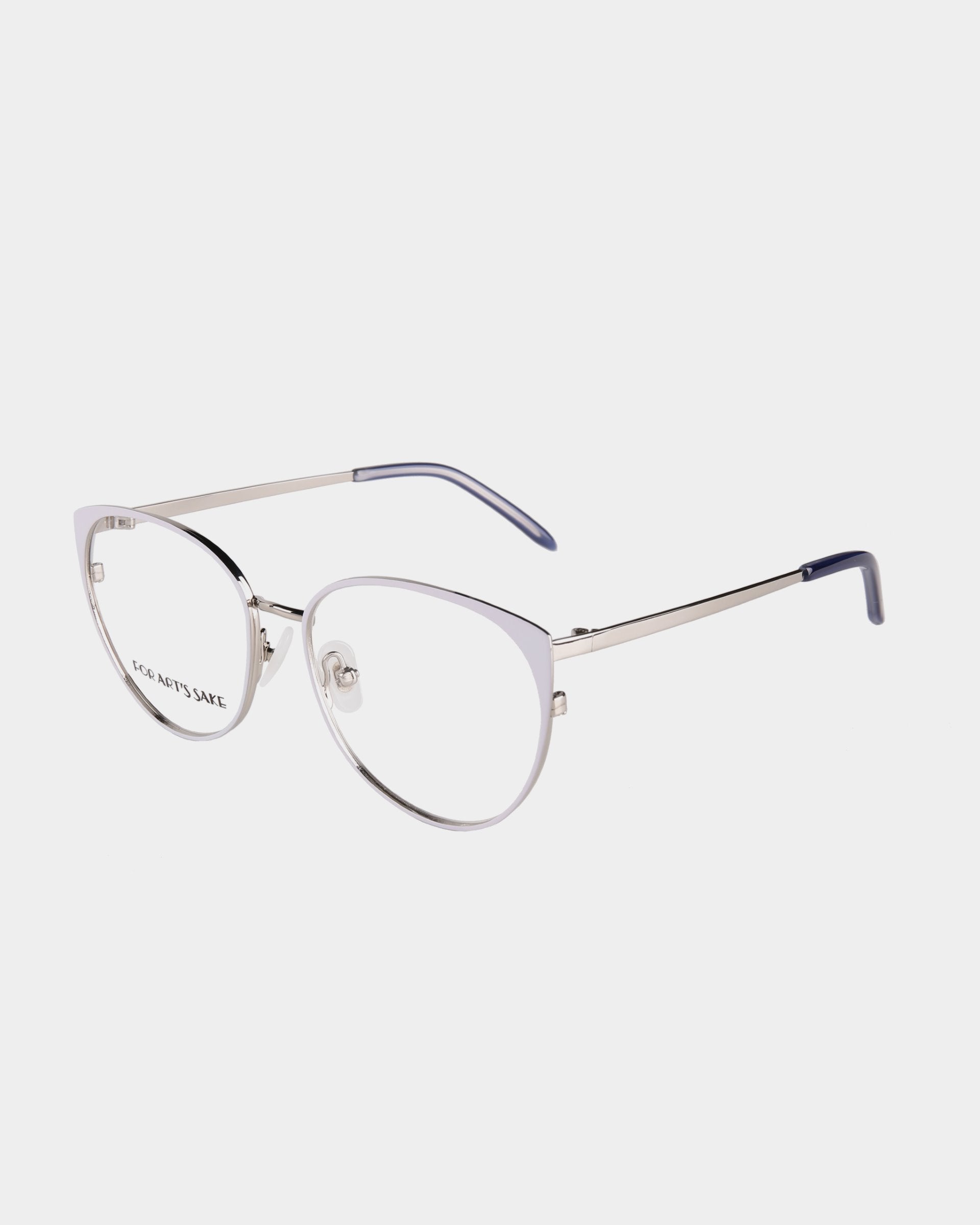 A pair of elegant, metallic-framed eyeglasses with a thin, cat-eye design and luxurious 18-karat gold plating. The temples are equipped with dark blue tips, and the nose pads are transparent. The right lens has subtle text inscribed on it. The background is white.

Product Name: Kaia
Brand Name: For Art&#39;s Sake®