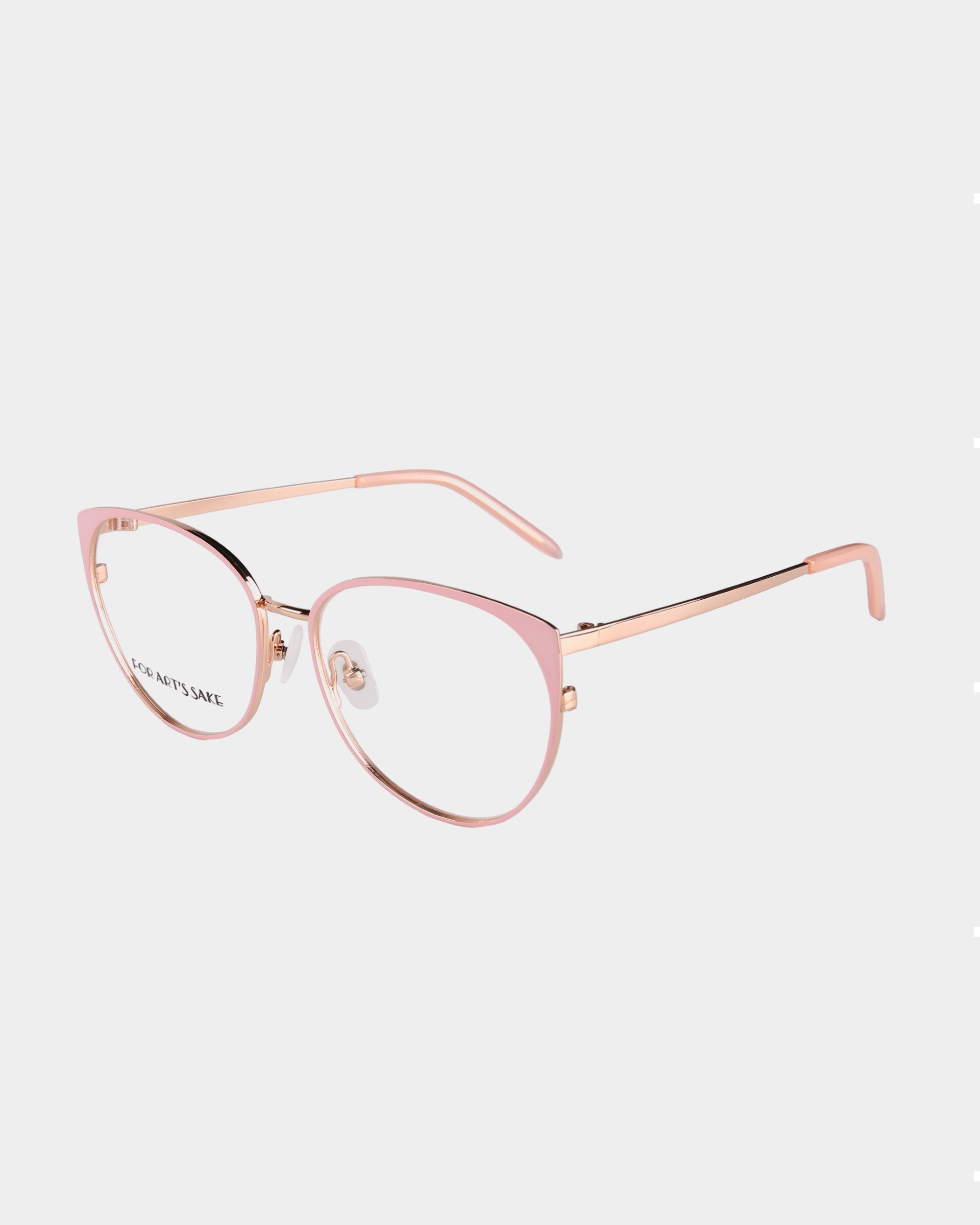A pair of stylish Kaia by For Art's Sake® with pink metal cat-eye frames and transparent lenses, featuring blue light filter technology. The temples are slender with a metallic finish that complements the frame color, while the white background enhances the simplicity and elegance of the design.