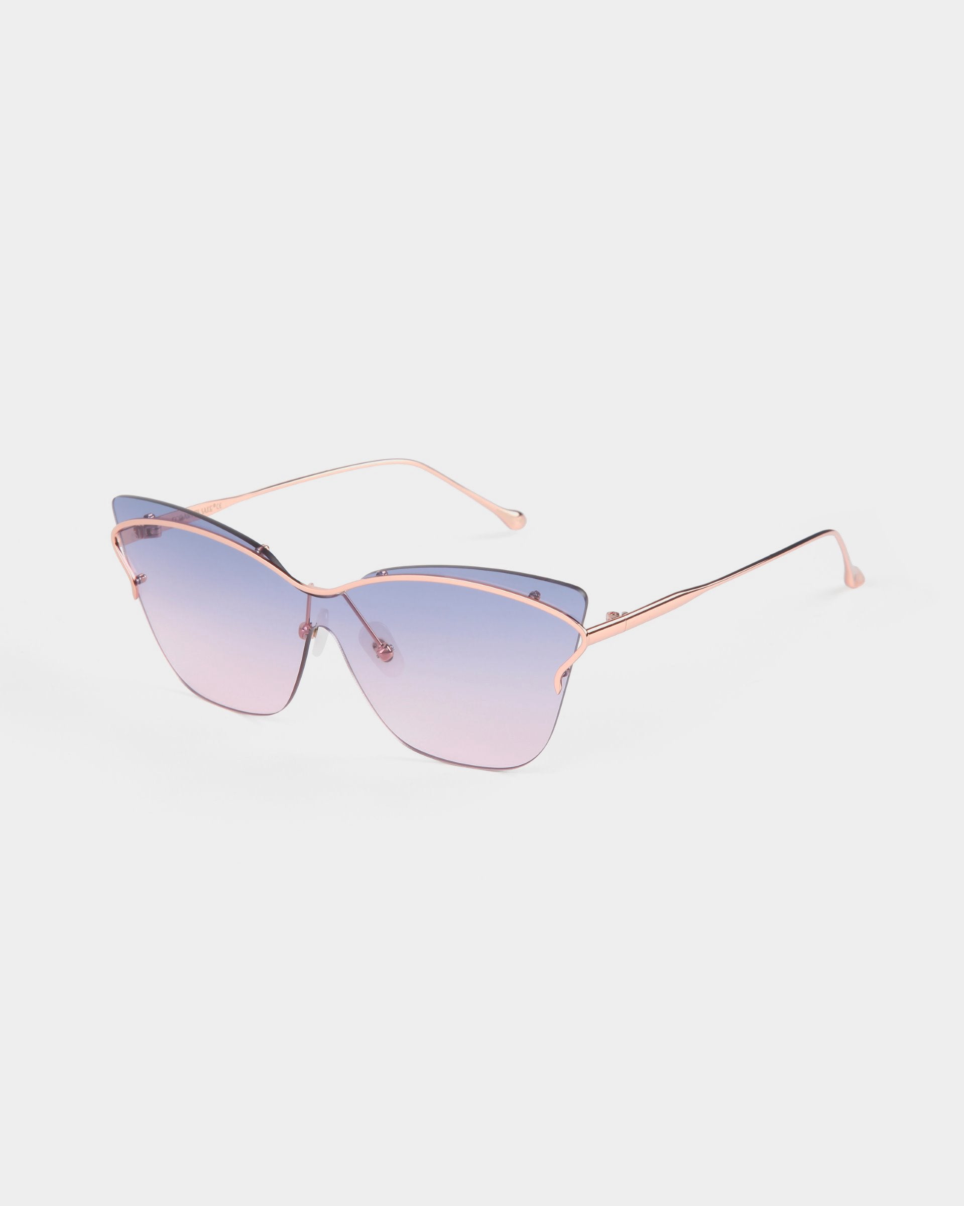 The Kelly by For Art's Sake® is a pair of stylish, retro-futuristic cat-eye sunglasses featuring gradient blue lenses and thin, elegant rose gold frames. The lenses are tinted from dark blue at the top to light blue at the bottom, and the frames boast a delicate, minimalistic design perfect for fashionable eyewear lovers.