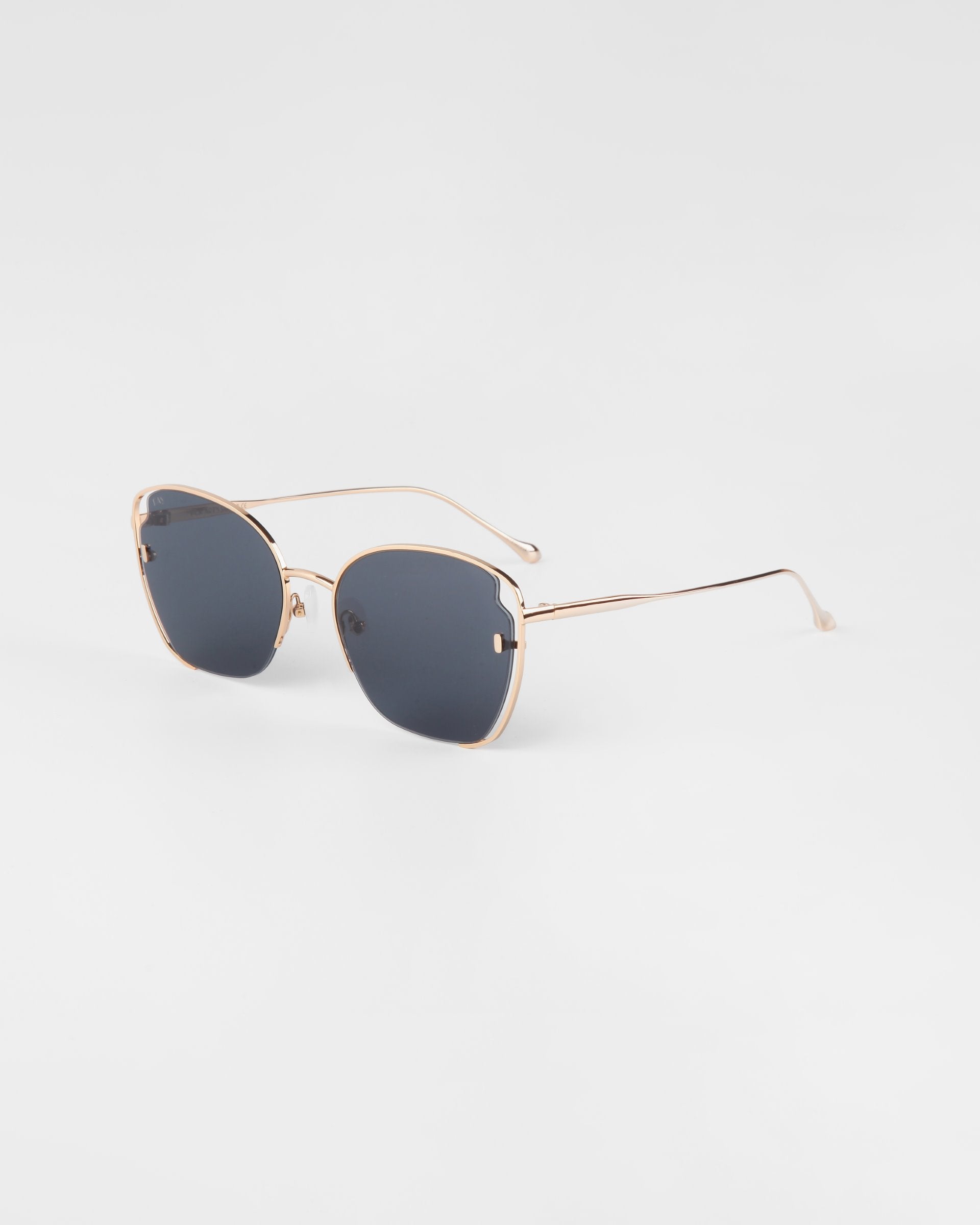 A pair of For Art&#39;s Sake® Eden sunglasses with 18-karat gold-plated frames and dark tinted lenses. The design features thin, elegant arms and a minimalistic yet modern aesthetic, set against a plain white background. Enjoy both style and protection with UVA &amp; UVB-protected lenses.