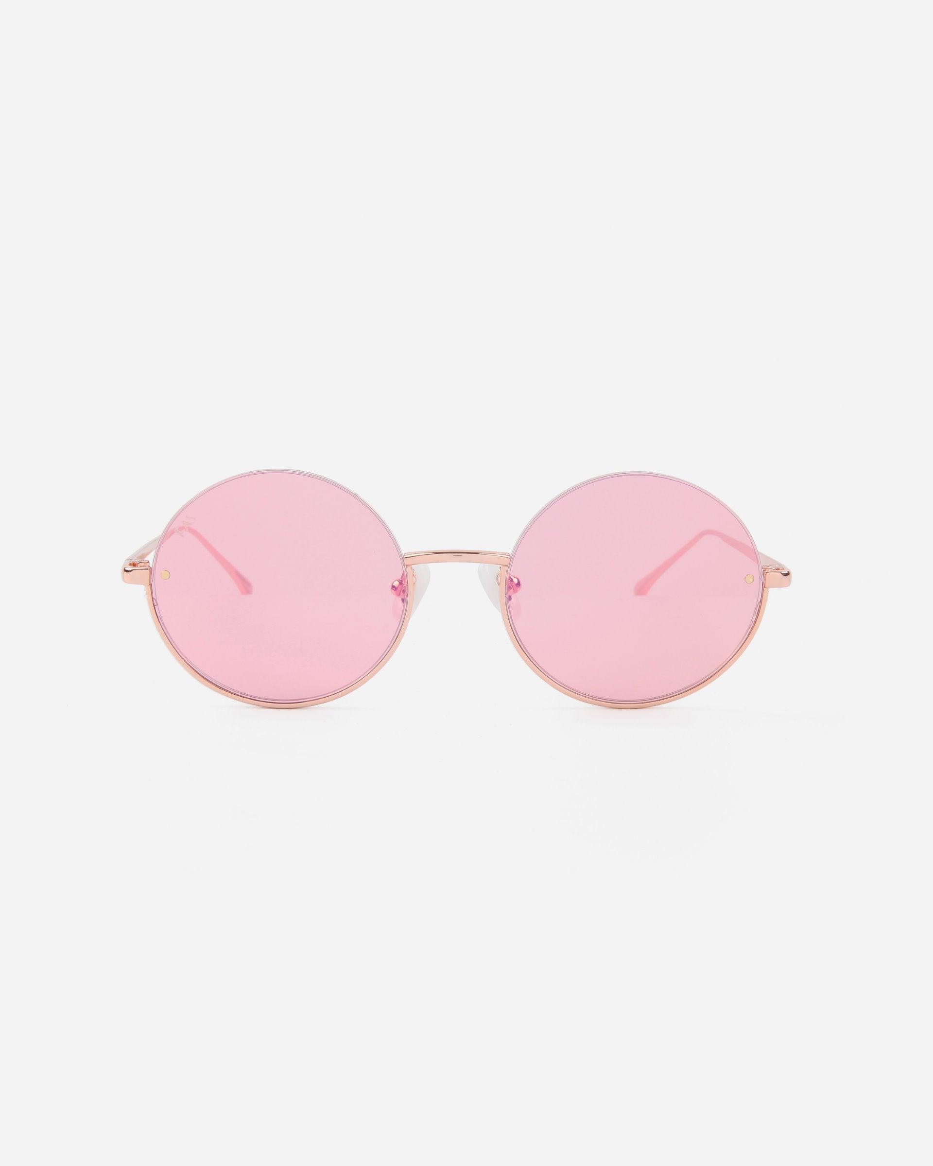 A pair of Skyline sunglasses by For Art&#39;s Sake® with pink-tinted, UVA &amp; UVB-protected Nylon lenses and thin gold stainless steel frames. The design is minimalist, with straight temples and no visible branding. The background is plain white, emphasizing the eyewear&#39;s trendy and stylish appearance.