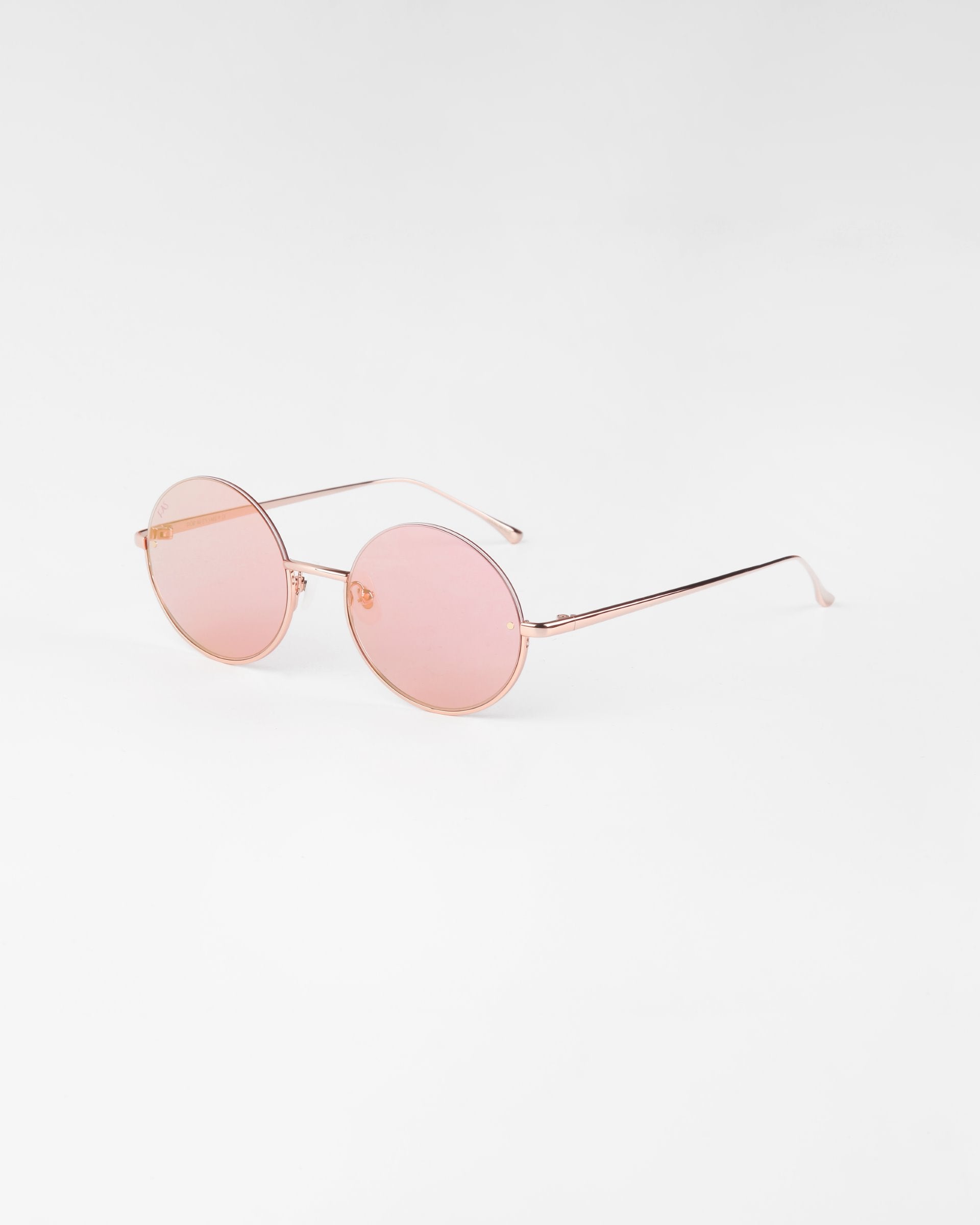 A pair of Skyline by For Art&#39;s Sake® round, pink-tinted sunglasses with slim, 18-karat gold-plated frames and temples. The minimalistic design features thin nose pads and lightweight construction with nylon lenses, all set against a plain white background.