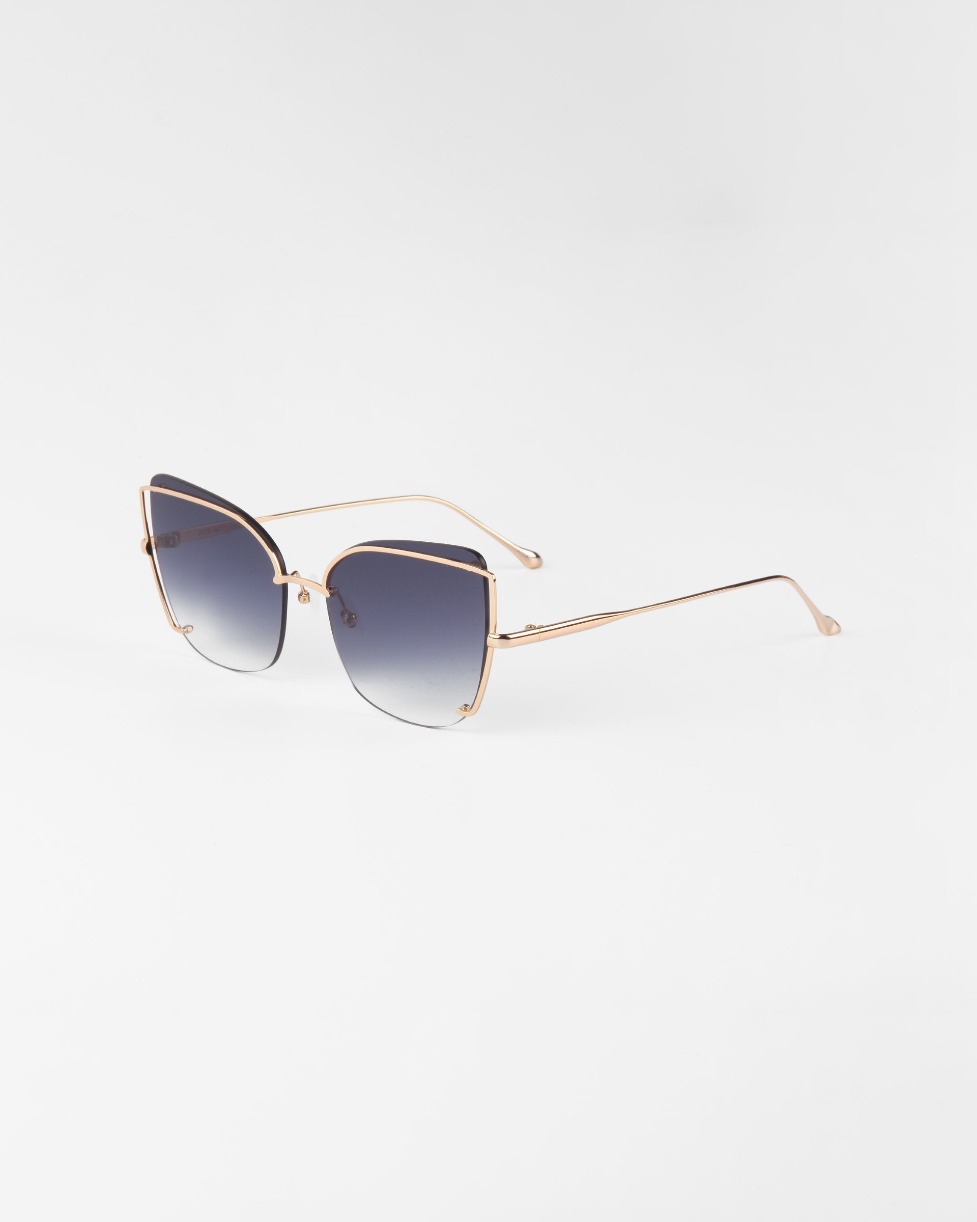 The Meow sunglasses by For Art&#39;s Sake® showcase a stylish cat-eye design with gradient dark nylon lenses and slender, gold-colored stainless steel frames. Adjustable nosepads ensure added comfort, while the plain white background accentuates their elegant and minimalistic aesthetic.