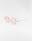 A pair of Meow sunglasses by For Art's Sake® showcasing pink-tinted nylon lenses and thin stainless steel frames with adjustable nosepads, positioned at an angle against a plain white background.