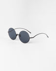 A pair of Oceana sunglasses by For Art's Sake® with black nylon lenses offering UVA & UVB protection and thin stainless steel arms is positioned against a plain white background.