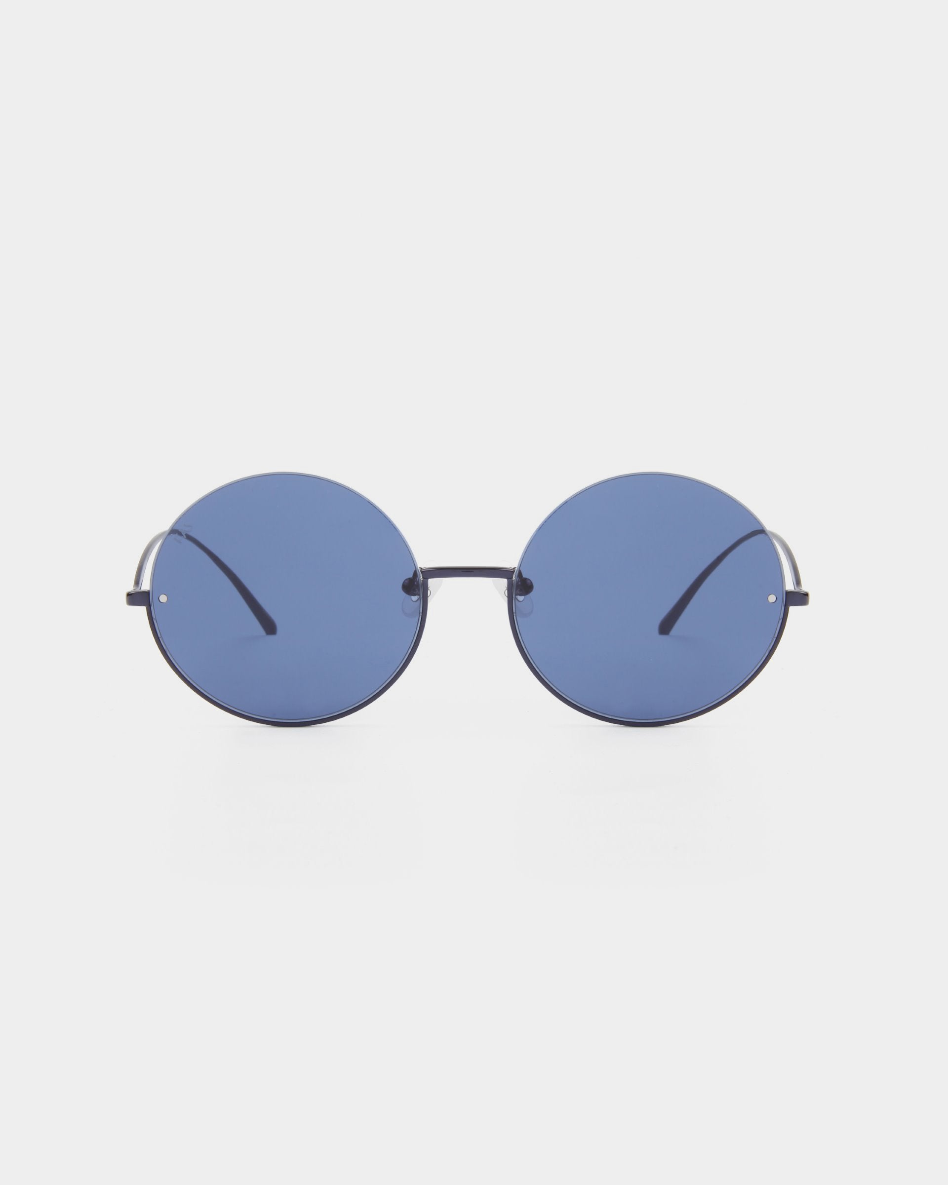 A pair of Oceana sunglasses from For Art&#39;s Sake® with dark blue-tinted nylon lenses that are 100% UVA &amp; UVB-protected and thin stainless steel frames. The arms are sleek and minimalist, blending seamlessly with the modern design of the eyewear. The background is plain white.