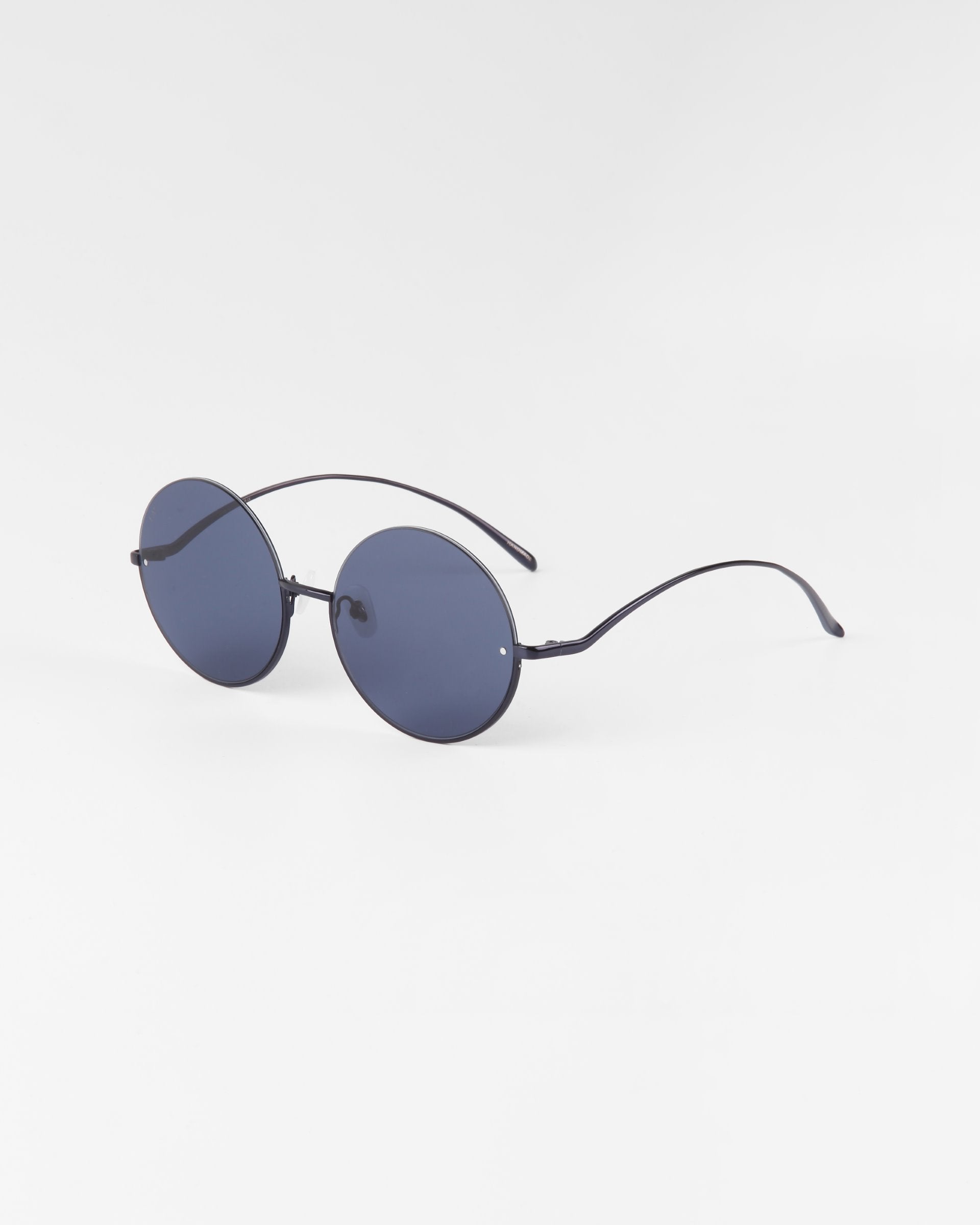 A pair of Oceana sunglasses by For Art&#39;s Sake® with thin stainless steel frames and arms is shown on a plain white background. The sunglasses have a minimalist design, appear lightweight, and feature nylon lenses that are 100% UVA &amp; UVB-protected.