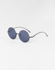 A pair of Oceana sunglasses by For Art's Sake® with thin stainless steel frames and arms is shown on a plain white background. The sunglasses have a minimalist design, appear lightweight, and feature nylon lenses that are 100% UVA & UVB-protected.