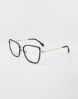 A pair of Lace eyeglasses by For Art's Sake® with a sleek black frame and 18-karat gold-plated arms. The glasses, featuring prescription lenses, rest on a white background, angled to show both the front and side views of the stylish frame.