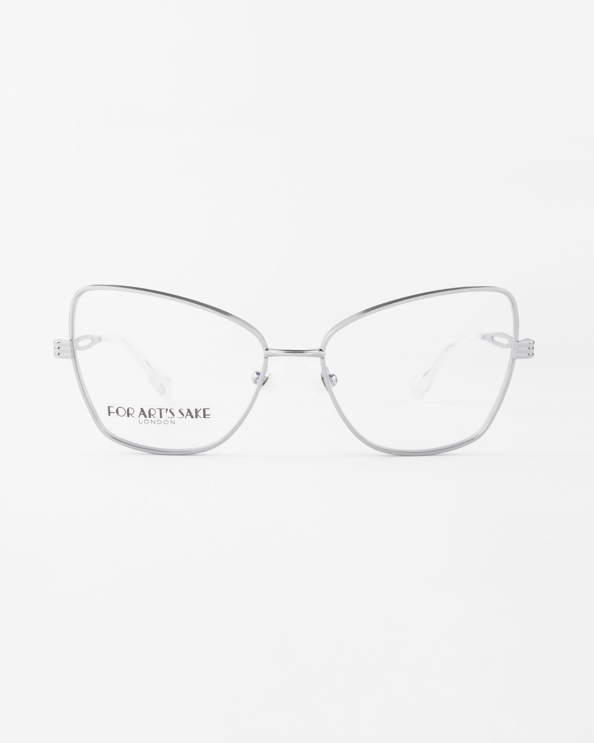 Clear cat-eye eyeglasses with thin, silver metal frames and the phrase "FOR ART'S SAKE LONDON" inscribed on the left lens. Featuring prescription lenses, these chic Lady by For Art's Sake® glasses are set against a plain white background.