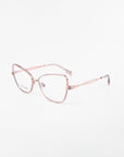 A pair of Lady eyeglasses by For Art's Sake® with thin, metallic rose gold frames and large, slightly rectangular lenses. Featuring blue light filter prescription lenses, the glasses rest on a white background, showcasing small nose pads and slender, intricately designed side temples for a modern and elegant look.