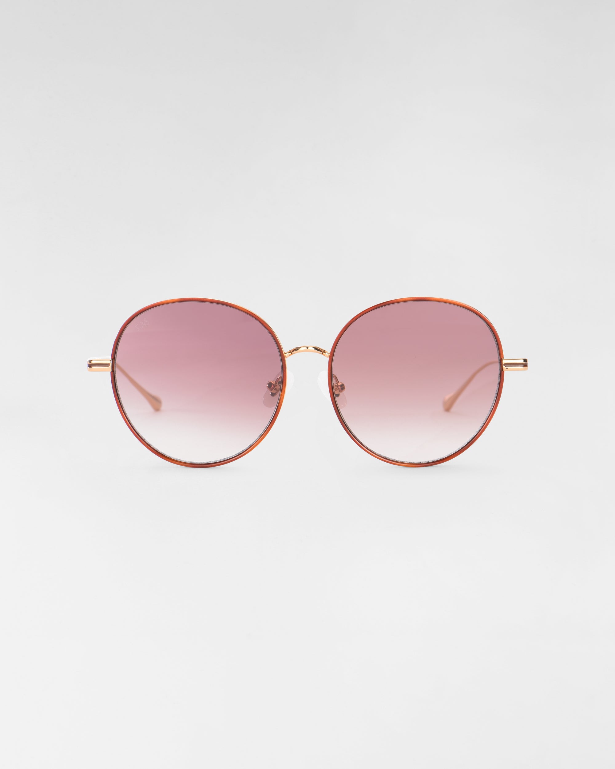 A pair of round sunglasses from For Art's Sake® called "Lemon," featuring thin, 18-karat gold-plated frames and pink-tinted gradient lenses. The background is light gray and the sunglasses are centered in the image.