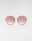 A pair of round sunglasses from For Art's Sake® called "Lemon," featuring thin, 18-karat gold-plated frames and pink-tinted gradient lenses. The background is light gray and the sunglasses are centered in the image.