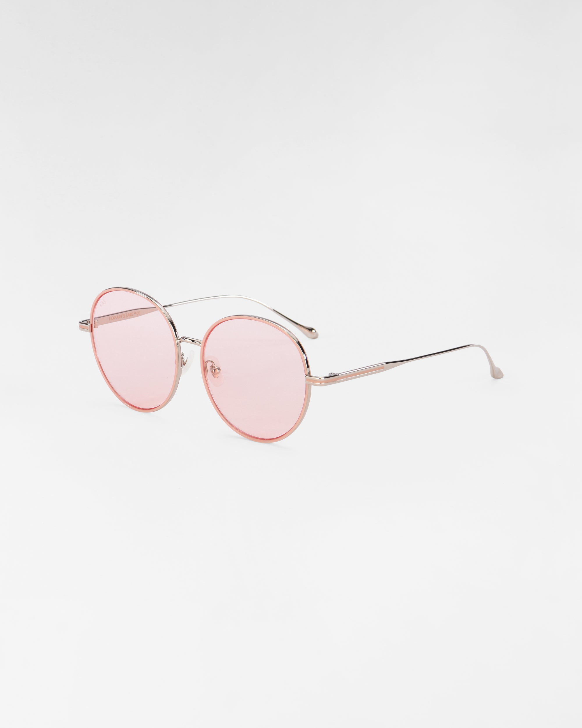 The Lemon sunglasses by For Art&#39;s Sake® feature round lenses with thin, 18-karat gold-plated frames and light pink tinted lenses. The temples have a slight curve at the ends, complemented by jadestone nose pads. The background is plain white.