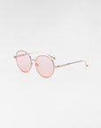 The Lemon sunglasses by For Art's Sake® feature round lenses with thin, 18-karat gold-plated frames and light pink tinted lenses. The temples have a slight curve at the ends, complemented by jadestone nose pads. The background is plain white.