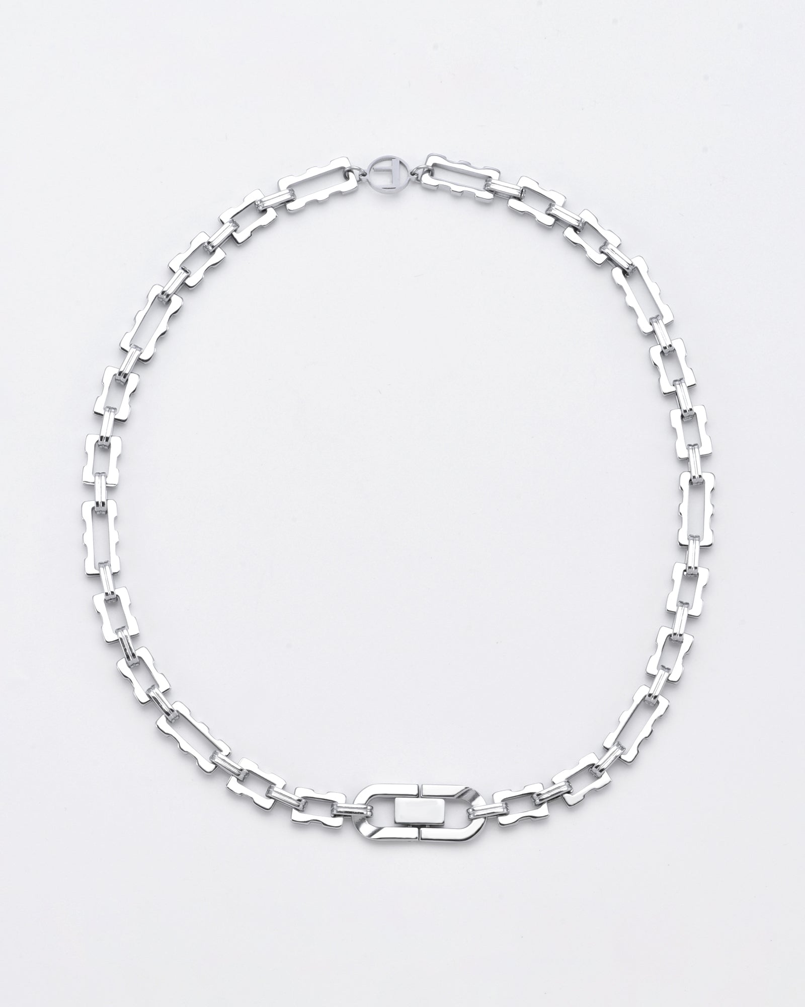 A silver Links Necklace Silver from For Art&#39;s Sake® with rectangular links arranged in a repeating pattern. The necklace has a sleek and modern design, featuring a distinctive rectangular clasp at the front. The background is plain white, highlighting the necklace&#39;s 24k gold-plated polished finish.