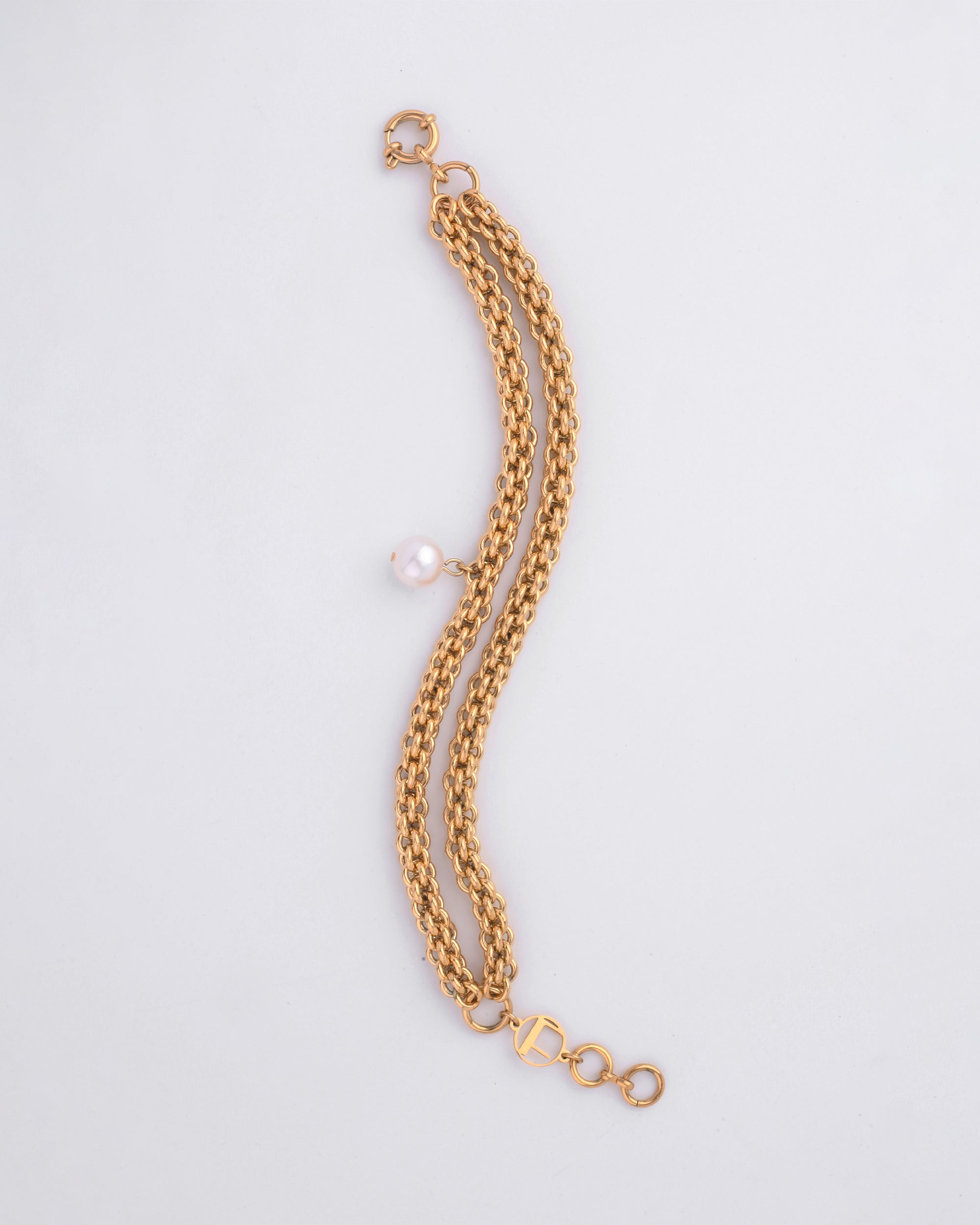 The For Art&#39;s Sake® Miller Bracelet features two strands intertwined together. One strand has a single freshwater pearl charm, adding a touch of elegance. The 18kt gold-plated bracelet boasts an adjustable loop segment for sizing and a clasp for fastening, all set against a plain white background.