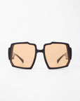 A pair of stylish black square-framed Moritz by For Art's Sake® with light brown tinted, UV-protected lenses. Featuring a chunky acetate frame and subtle gold-plated inlay, the Moritz sunglasses are displayed against a plain white background, giving a clear view of their modern and sleek design.