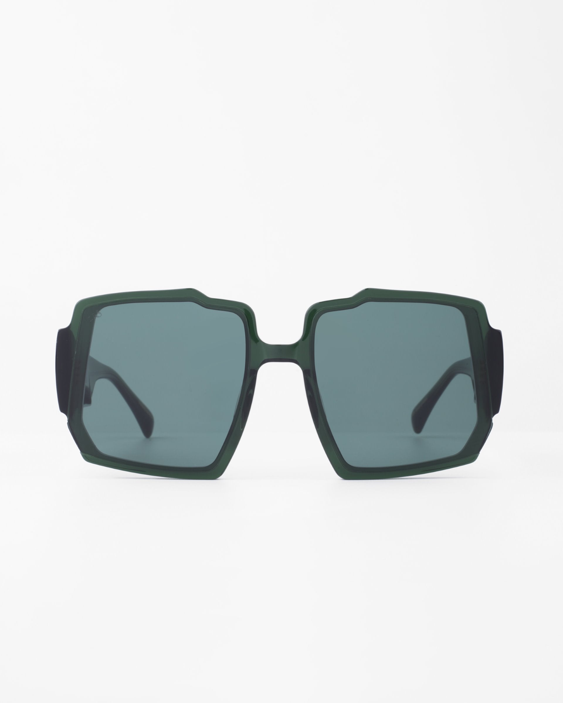A pair of dark green rectangular sunglasses with blue-tinted, UV-protected lenses. The oversized frames, featuring a chunky acetate frame and black temples, boast a bold, angular design. The Moritz by For Art&#39;s Sake® stands out against the plain white background.