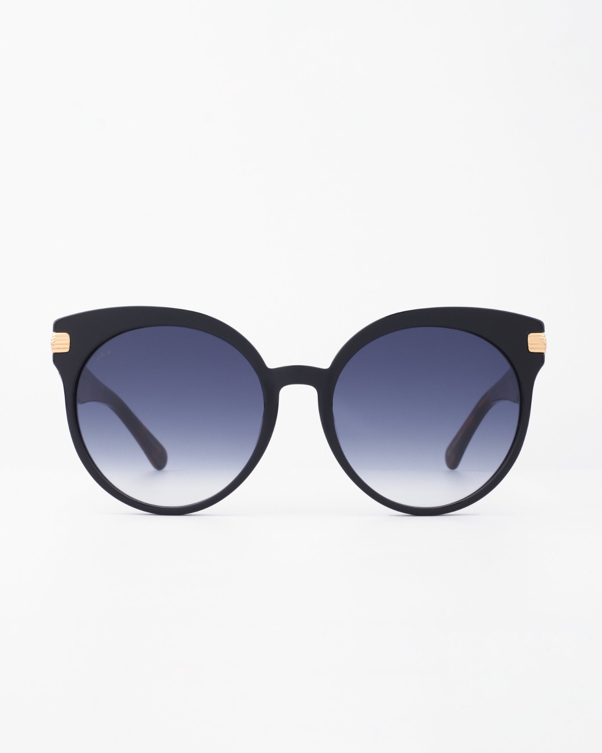 A pair of For Art&#39;s Sake® Muse sunglasses with round, shatter-resistant nylon lenses that transition from dark at the top to lighter at the bottom. The arms, crafted from handmade plant-based acetate, feature an 18-karat gold-plated temple near the hinges. The background is plain white.