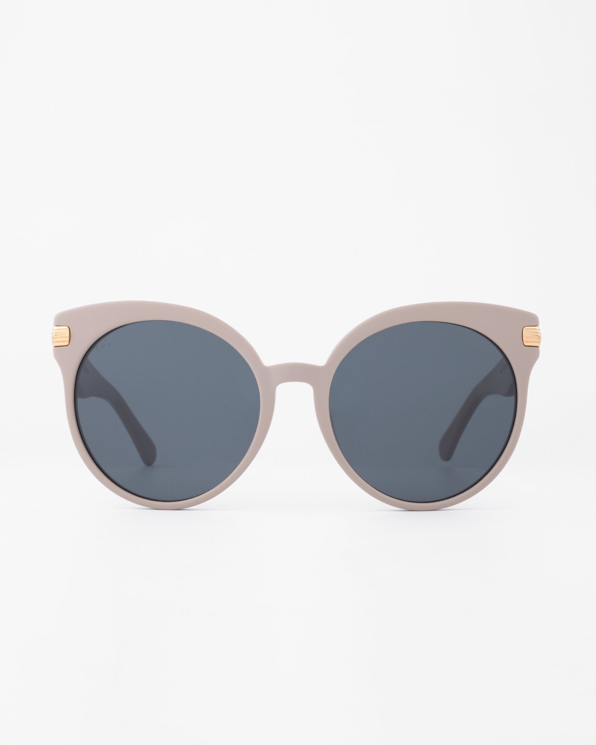 A pair of round, oversized Muse sunglasses with beige frames and dark-tinted, shatter-resistant nylon lenses from For Art&#39;s Sake®. The handmade plant-based acetate frames have 18-karat gold-plated accents on the temples. The sunglasses are set against a plain white background.