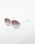 A pair of stylish For Art's Sake® Mars sunglasses with round, semi-transparent pink frames and metallic hinges. The shatter-resistant nylon lenses have a gradient tint that transitions from dark to light, offering UVA & UVB protection. Thin, gold-plated stainless steel temples with hooked ends ensure a secure fit.