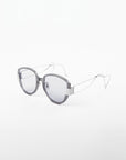 A pair of For Art's Sake® Mars sunglasses with round, shatter-resistant nylon lenses that are gray-tinted and thin, metal arms. The frame around the lenses is thick and translucent gray, while the arms are sleek silver with a minimalist, modern design. The background is a plain white.