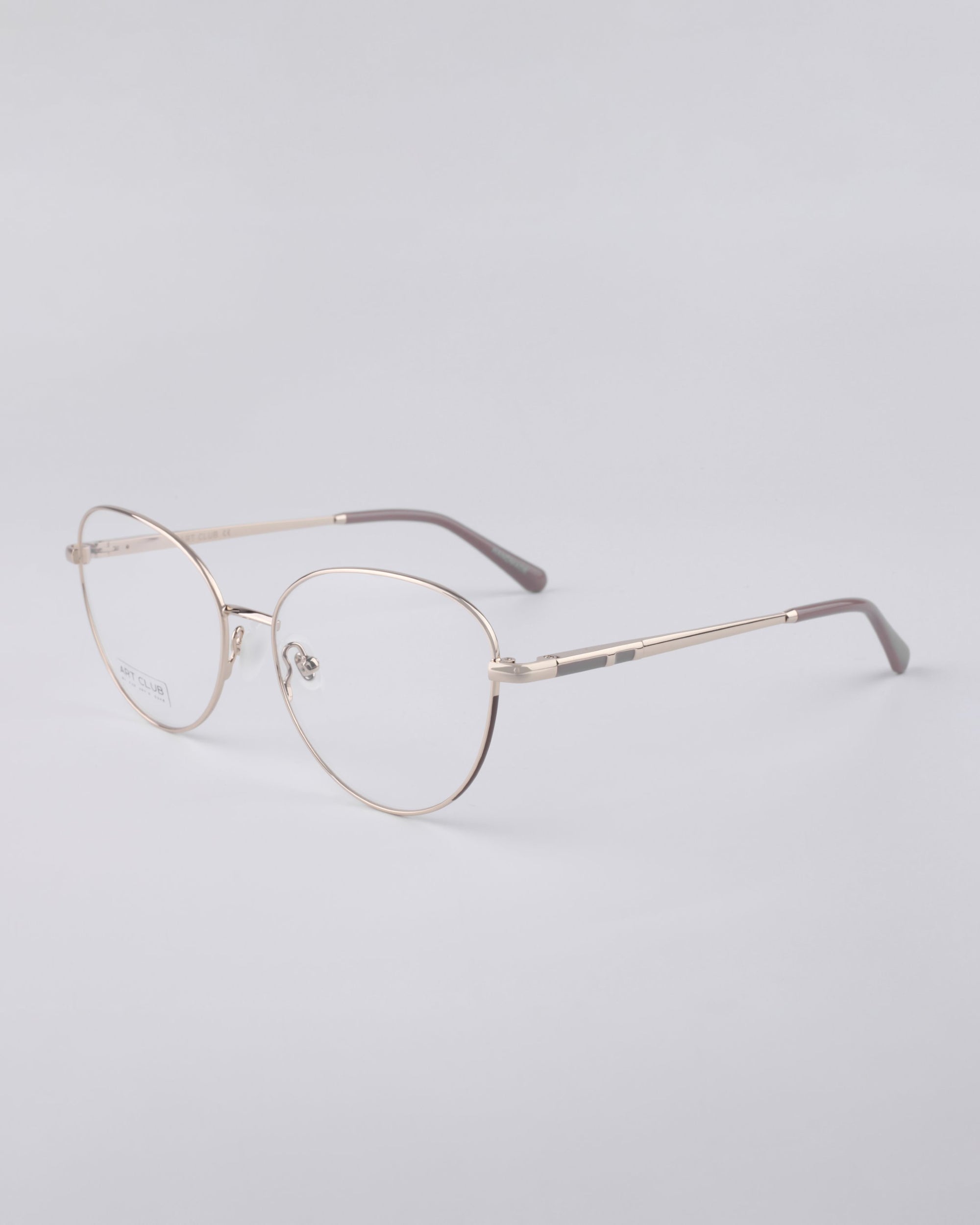 A pair of For Art's Sake® Millie frames, showcasing a thin metal build and round lenses, is set against a light gray background. These eyeglasses exemplify a sleek, minimalist design with blue light filter lenses, adjustable nose pads, and cushioned temple tips for maximum comfort.